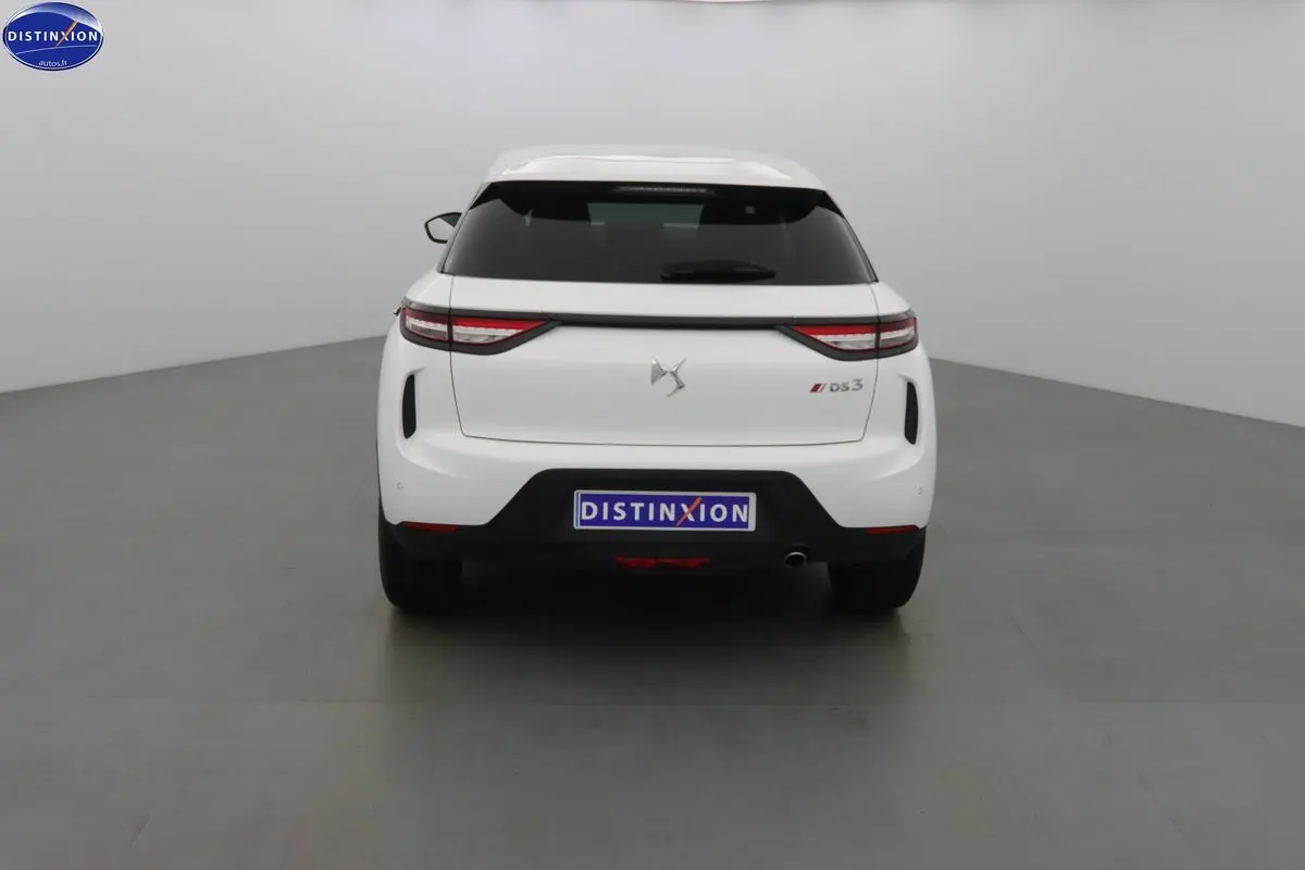 Vue arrière d'une DS3 Crossback blanche Banquise avec feux LED et vitre arrière teintée dans un studio.