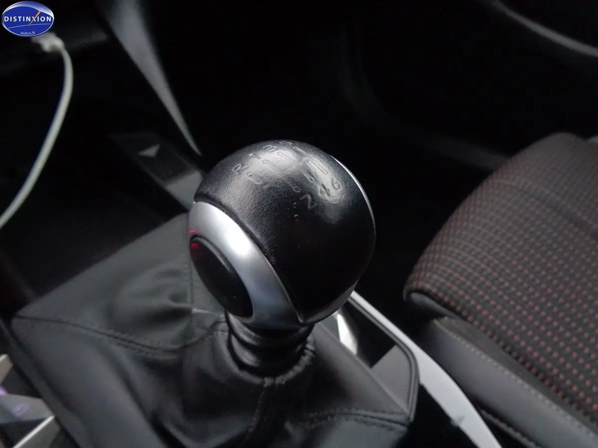 Gros plan sur le levier de vitesse manuel noir du DS3 Crossback blanc banquise, avec siège avant à motifs visibles.