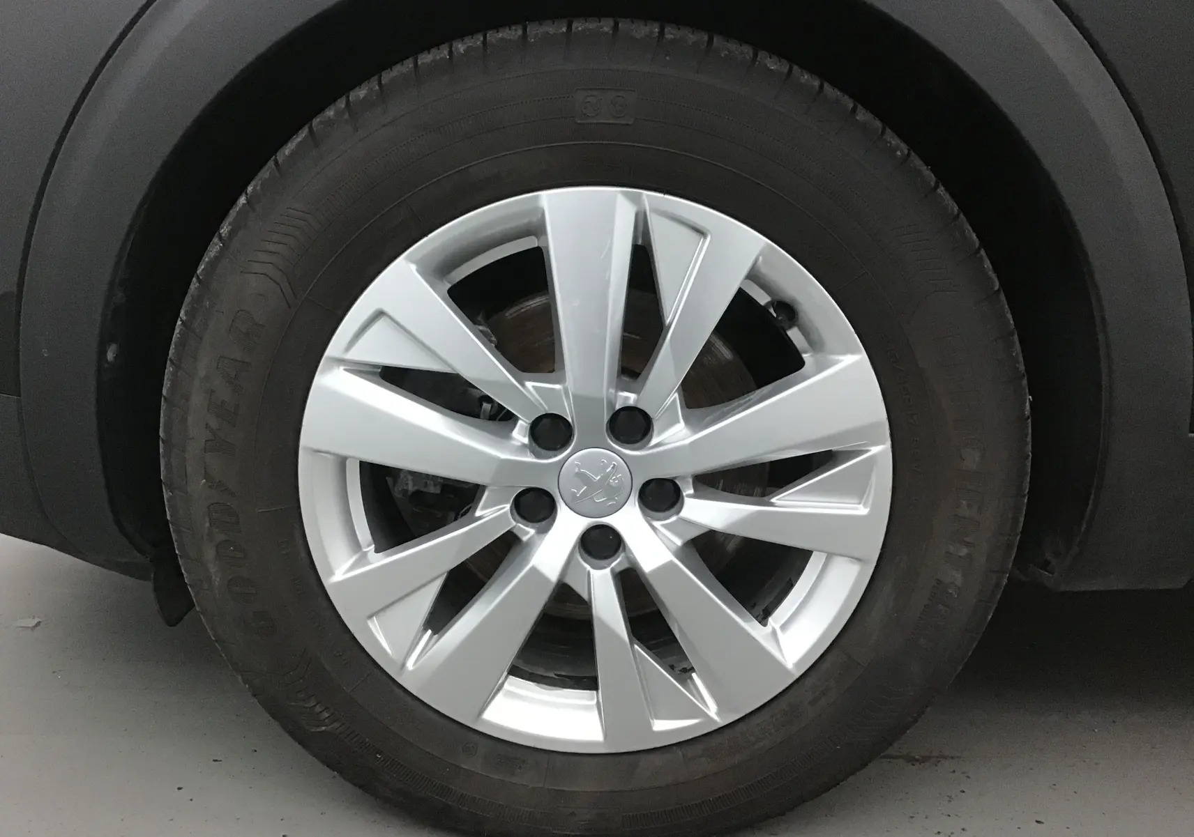 Gros plan sur la jante argentée de Peugeot 5008 noire, mettant en valeur le logo lion au centre du pneu Goodyear.