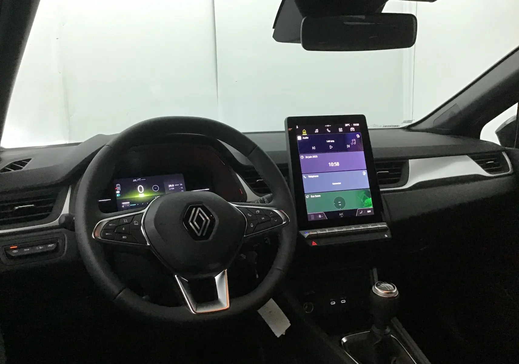 Vue intérieure du tableau de bord du Renault Captur 2025, avec volant multifonction et écran tactile central vertical.