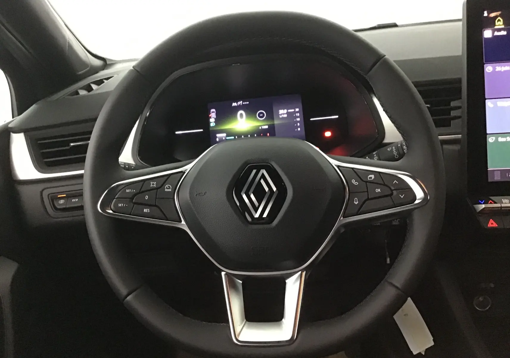 Volant multifonction noir avec logo Renault au centre, tableau de bord numérique et écran tactile latéral du Renault Captur 2025.