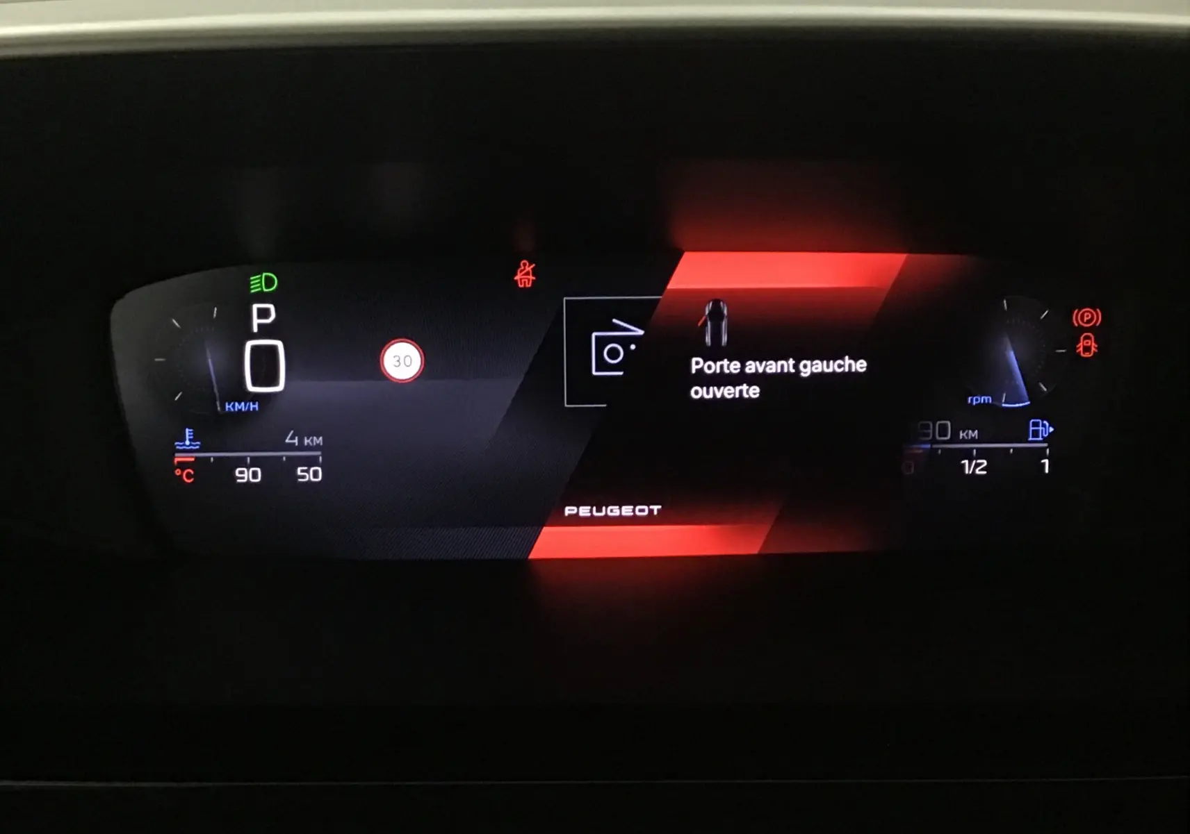 Tableau de bord numérique de Peugeot 308 gris Artense, affichant porte avant gauche ouverte et vitesse à zéro.