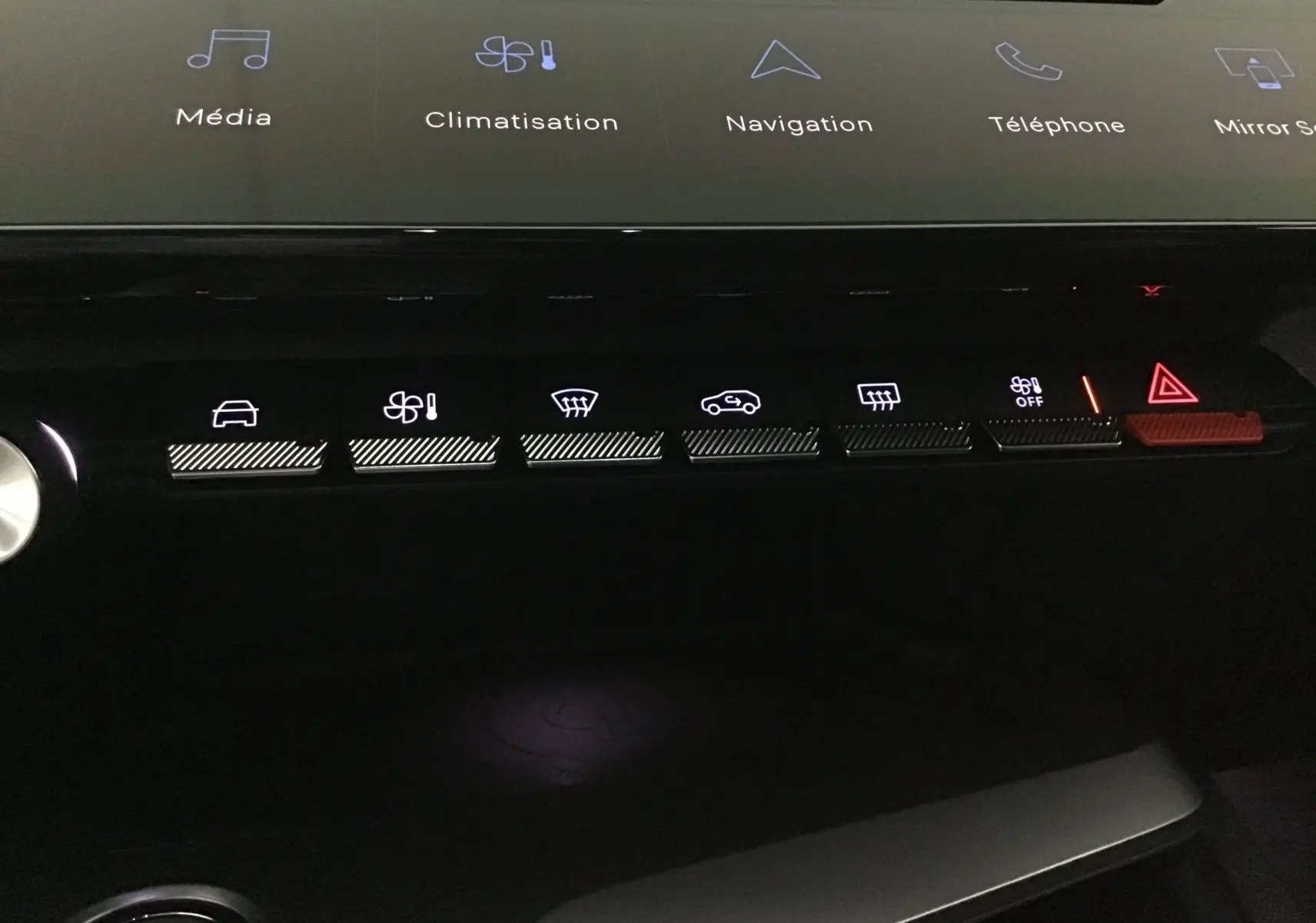 Vue rapprochée des commandes tactiles du tableau de bord de la Peugeot 308 gris Artense, avec éclairage des fonctions climatisation et sécurité.