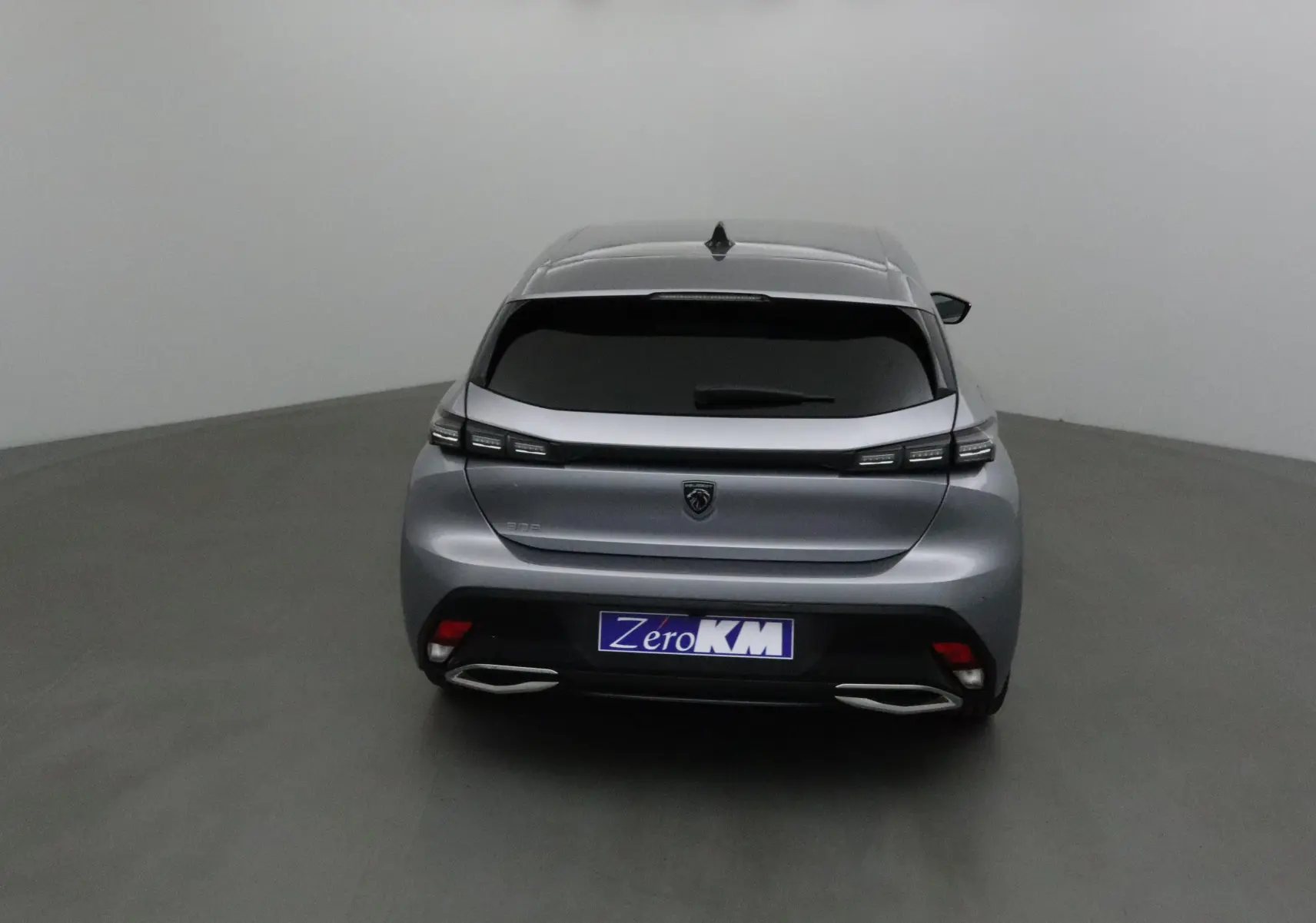 Vue arrière d'une Peugeot 308 gris Artense avec feux LED étirés et double sortie d'échappement chromée.