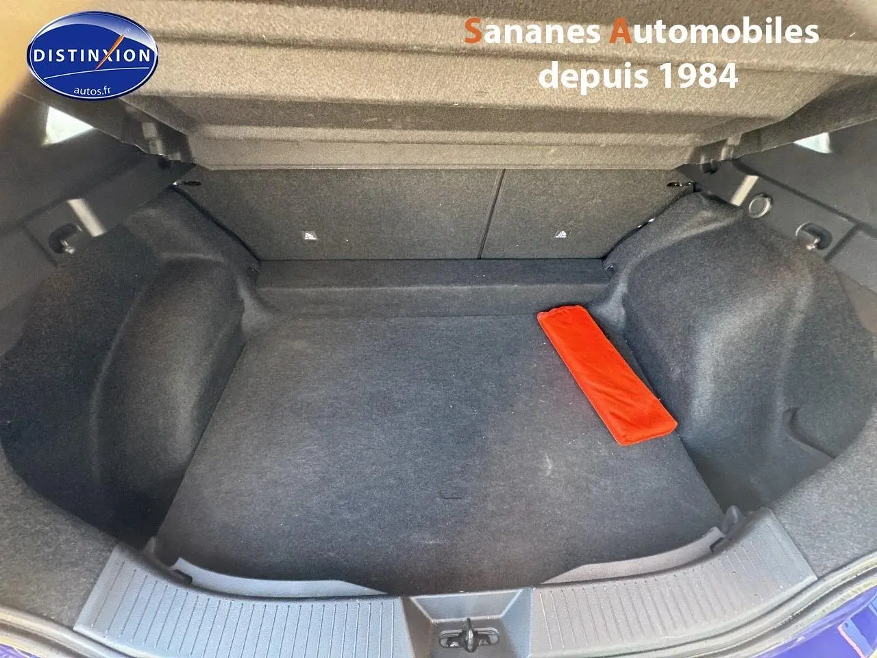 Coffre ouvert d'un Nissan Qashqai 1.5 e-Power bleu foncé, montrant un espace de rangement vide avec un objet rouge.