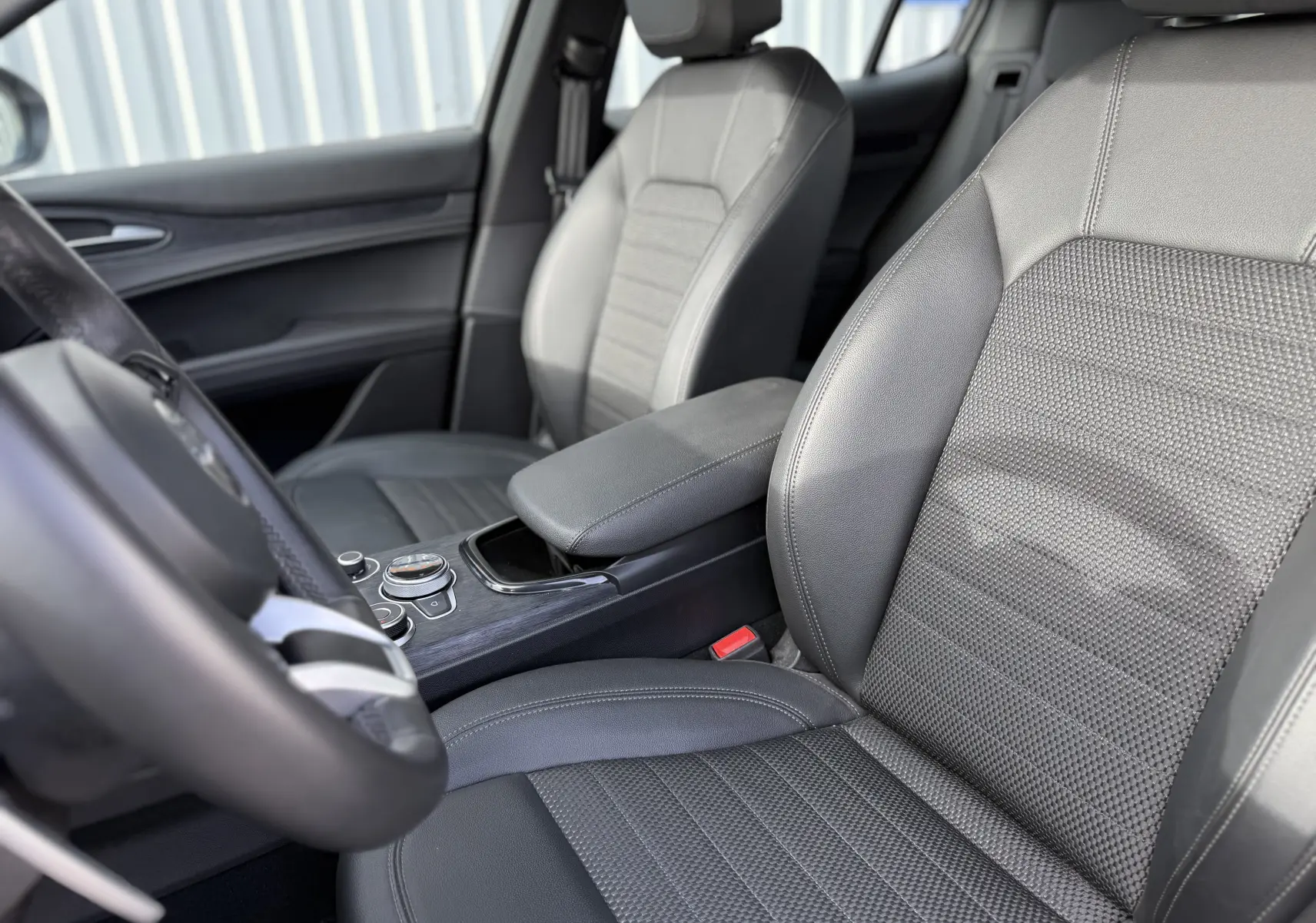 Intérieur de l'Alfa Romeo Stelvio 2023, vue côté conducteur sur les sièges en cuir gris et la console centrale.