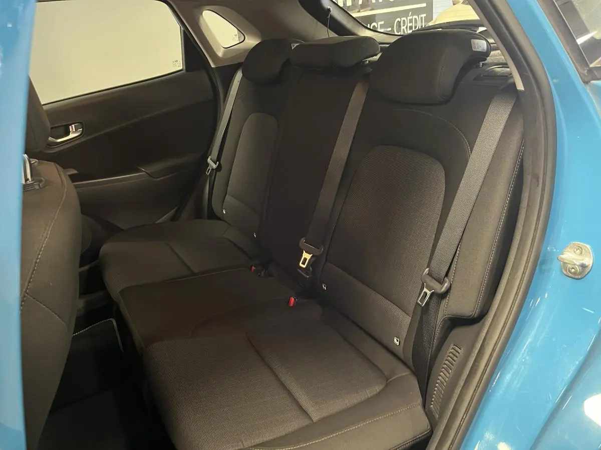 Vue intérieure côté droit sur les sièges arrière noirs du Hyundai Kona bleu 2022 avec porte ouverte.
