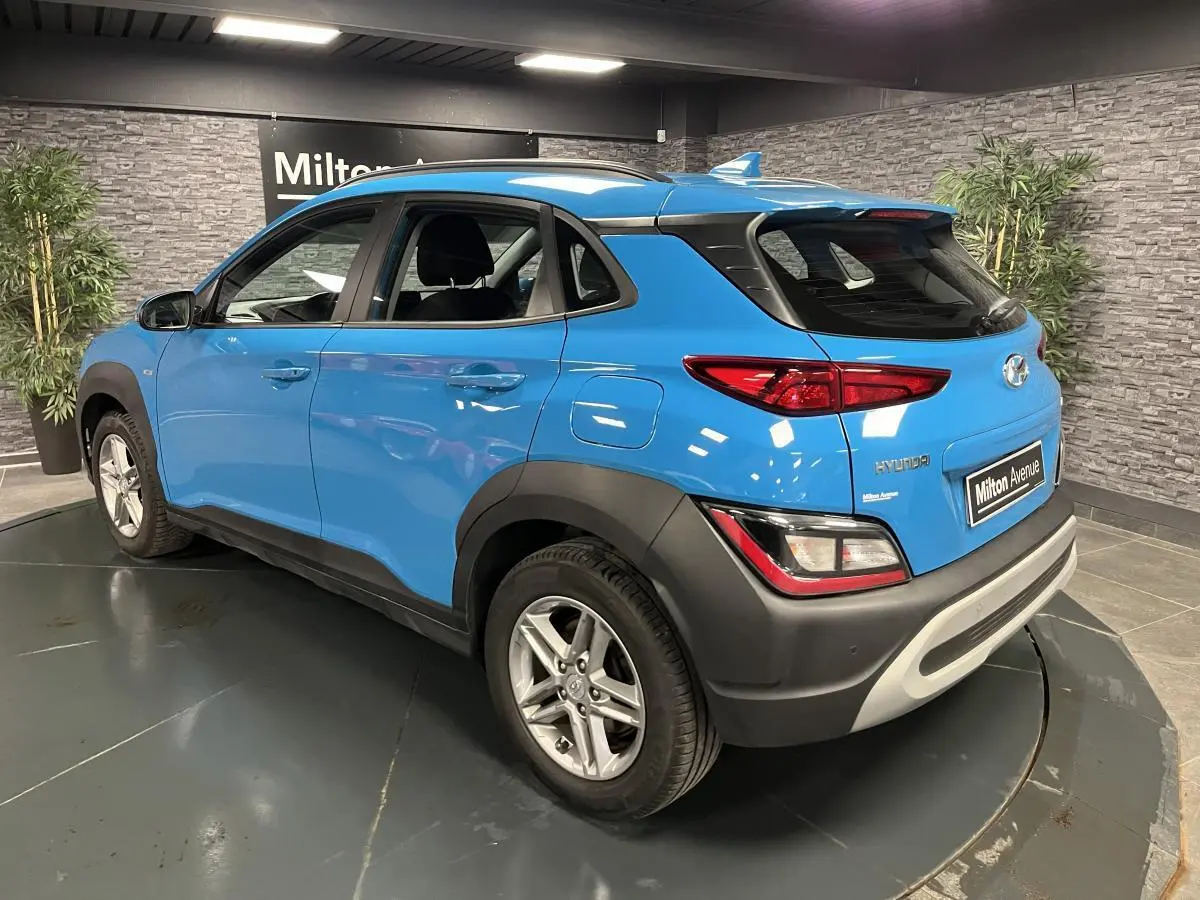 Vue 3/4 arrière droite d'un Hyundai Kona bleu avec protections noires et antenne aileron de requin.