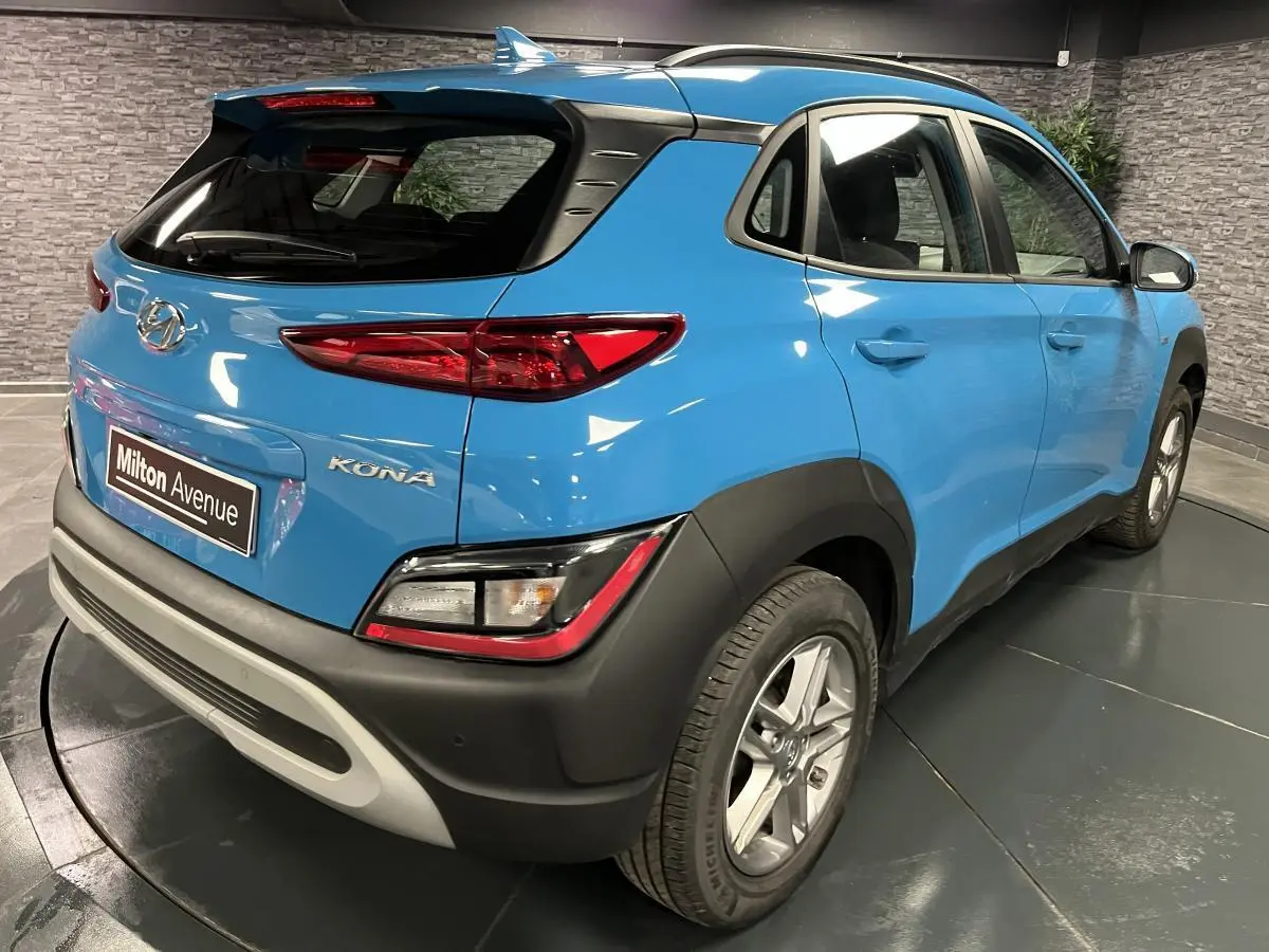 Vue 3/4 arrière droit d'un Hyundai Kona bleu avec protections noires et antenne aileron de requin.