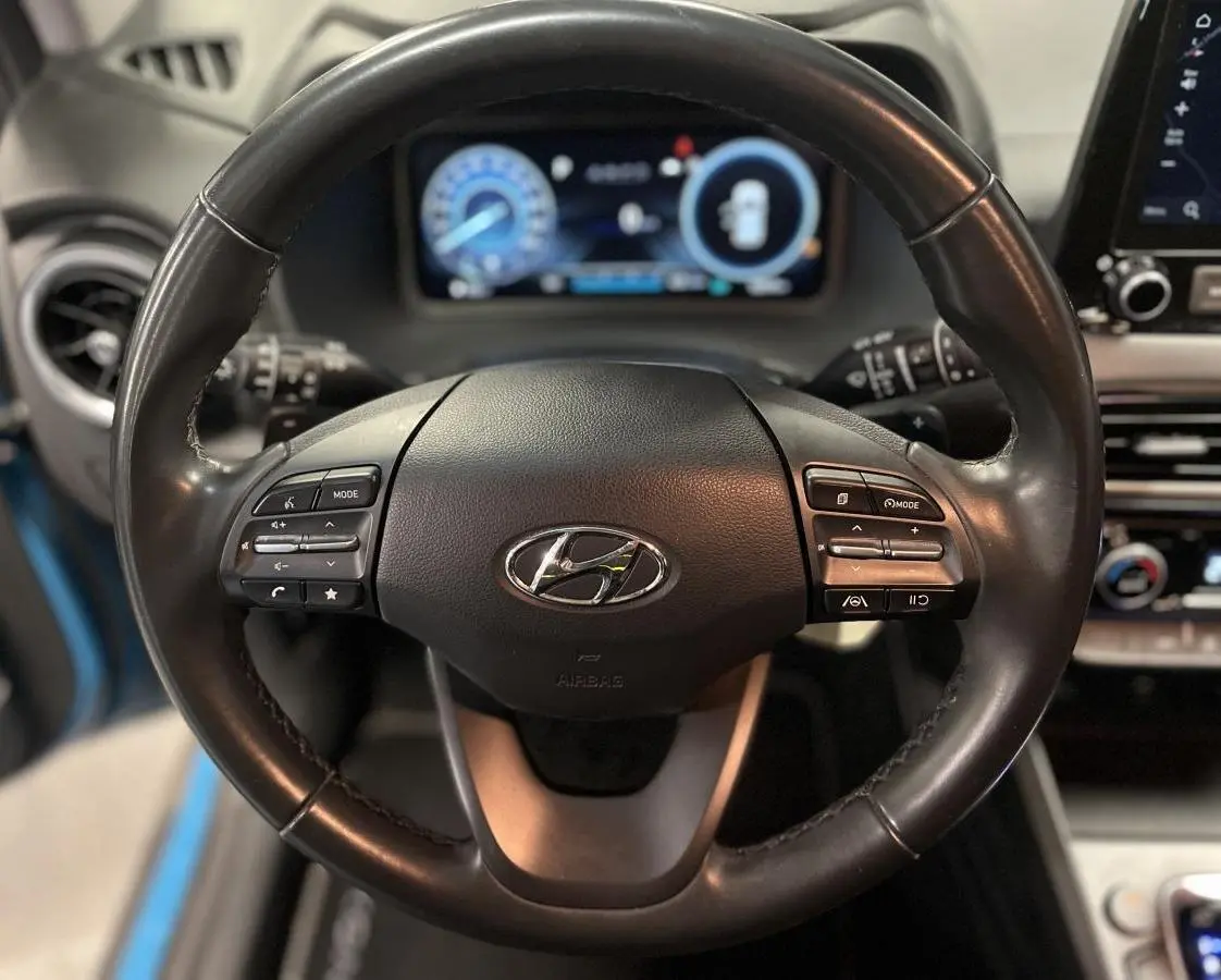 Volant cuir noir du Hyundai Kona 2022 avec commandes intégrées et tableau de bord numérique en arrière-plan.