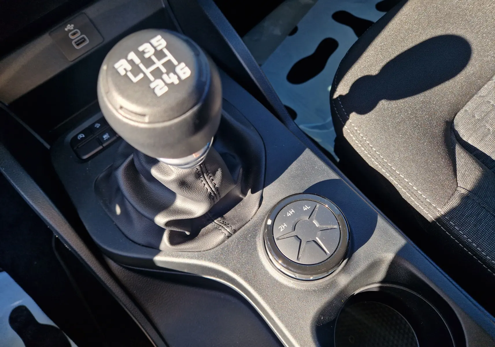 Gros plan sur le levier de vitesses manuel et la molette 4x4 du Ford Ranger Super Cabine gris Iconic, intérieur noir.
