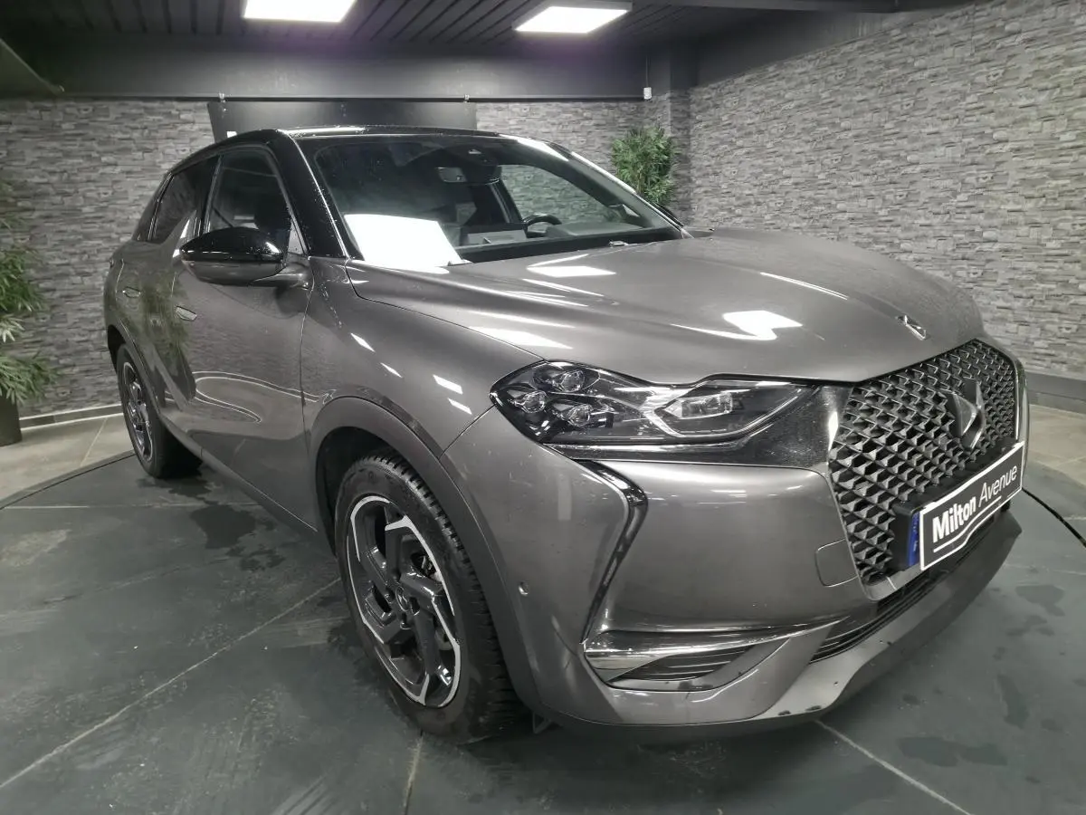 Vue 3/4 avant droite d’un DS3 Crossback gris métallisé avec calandre DS Wings chromée dans un showroom.