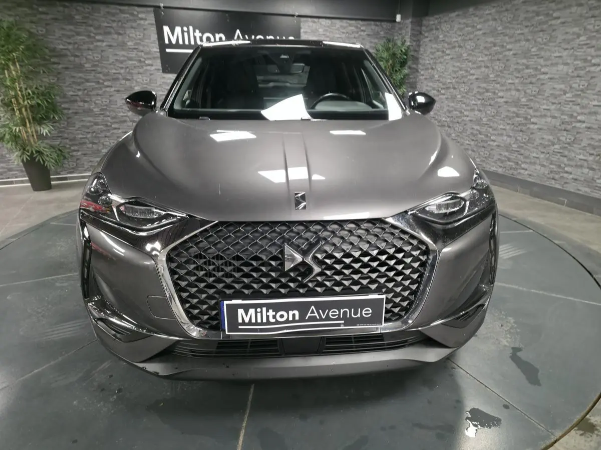 Vue frontale d'un DS3 Crossback gris métallisé avec calandre DS Wings chromée et phares LED, en showroom.