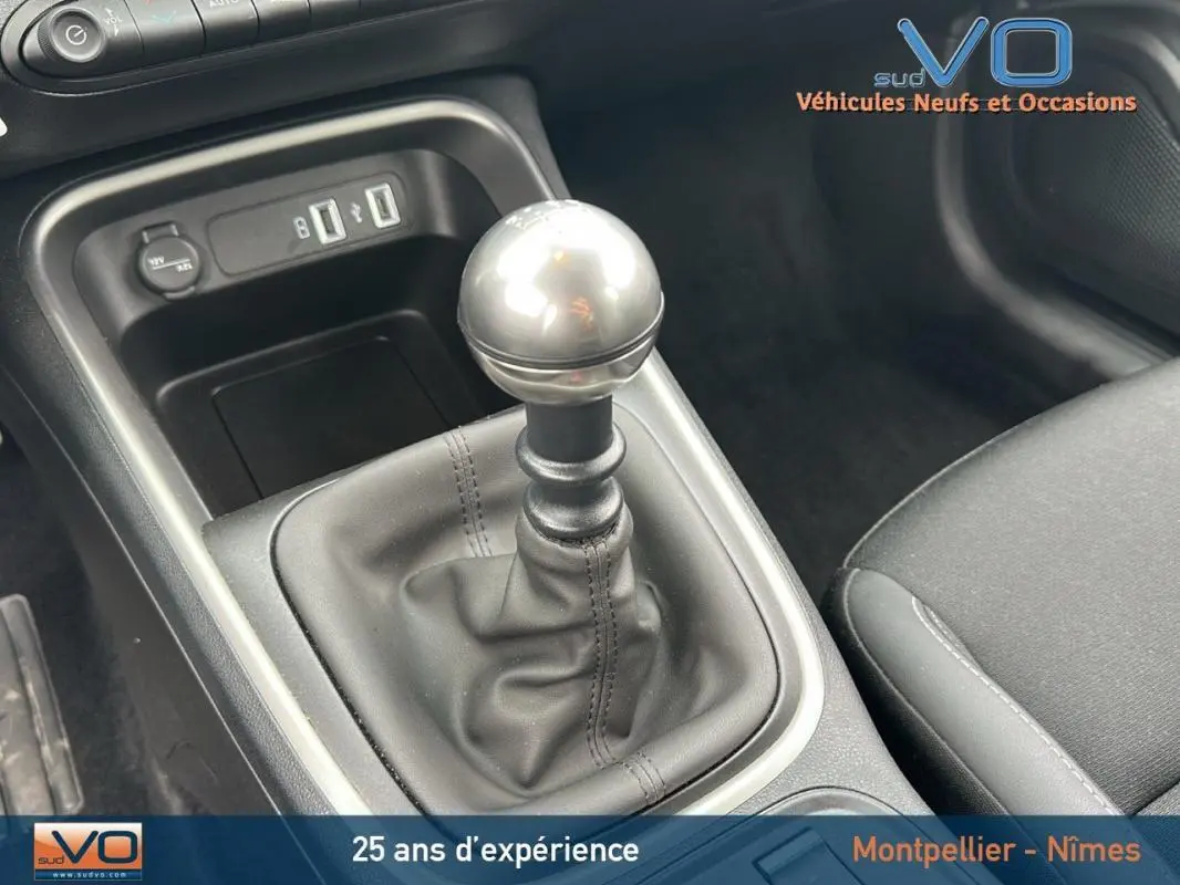 Gros plan sur le levier de vitesses manuel du Jeep Avenger gris foncé 2024, avec ports USB et prise 12V visibles.