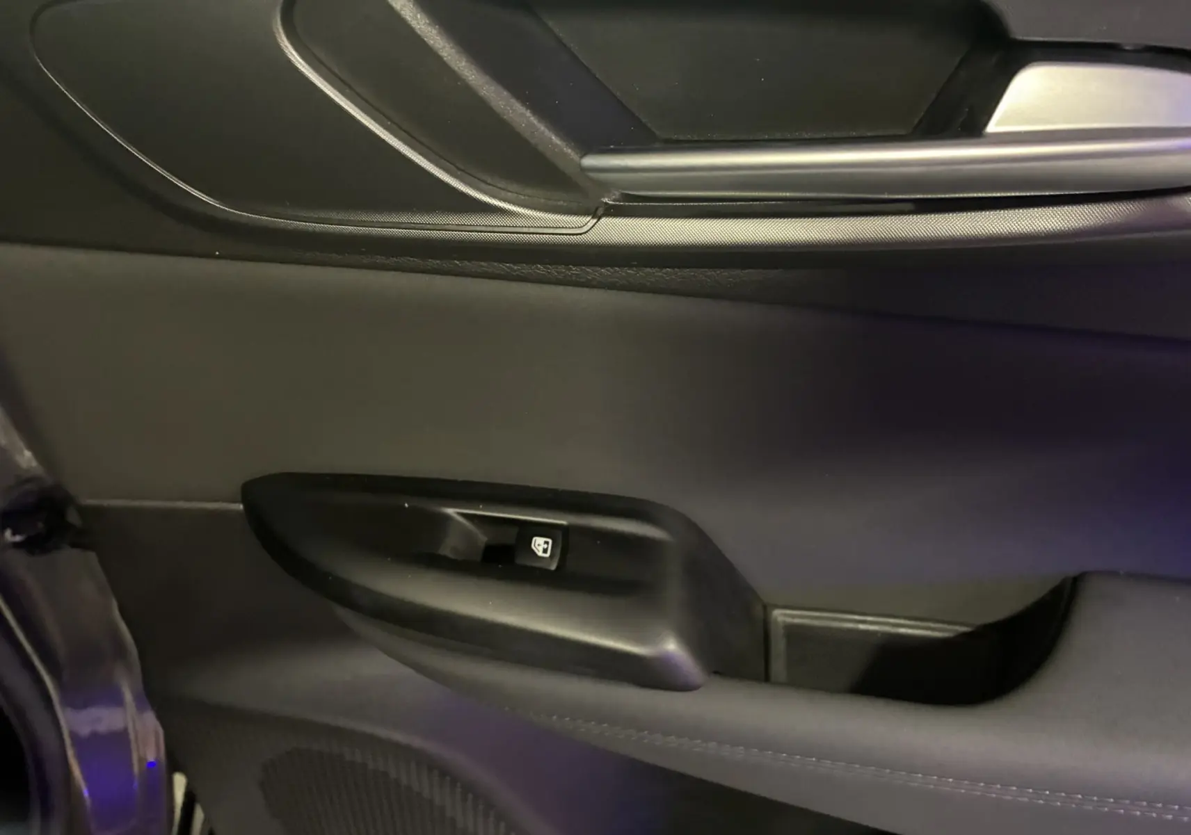 Détail de la porte intérieure côté gauche de l'Alfa Romeo Tonale gris foncé avec commande de vitre électrique.