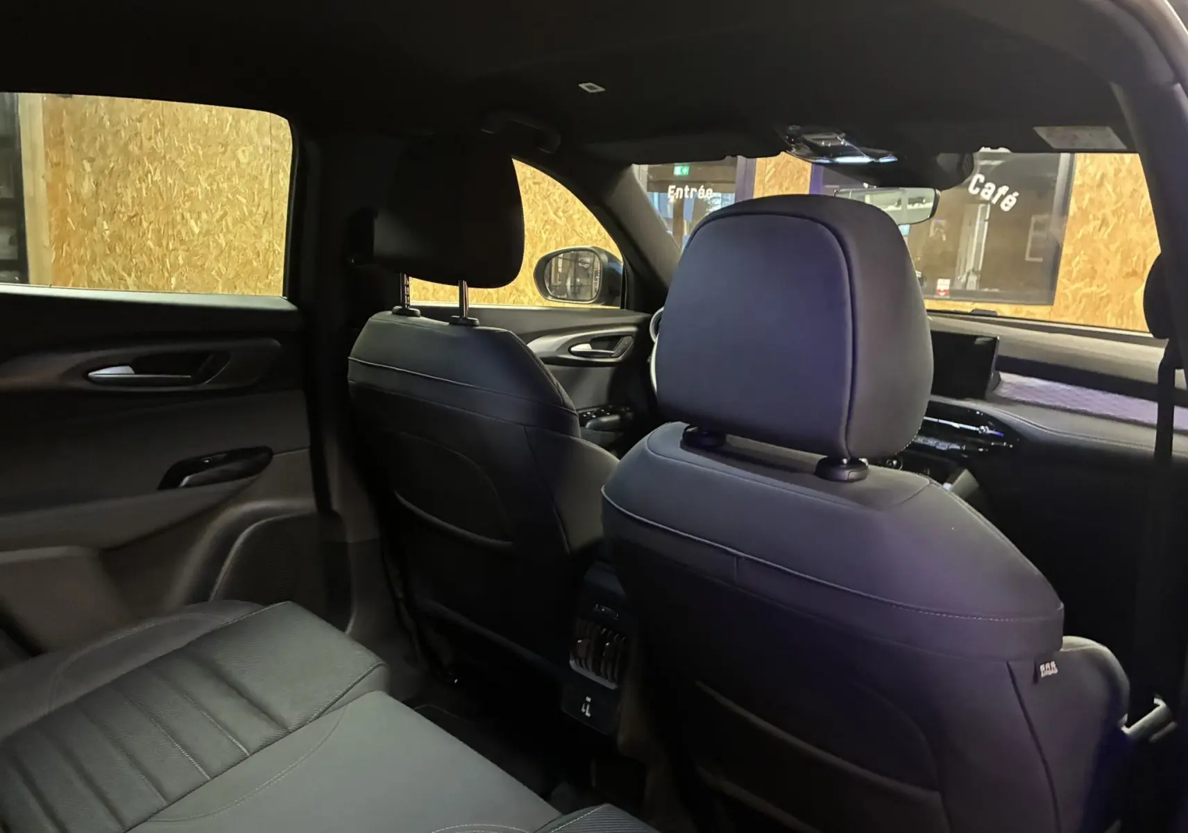 Vue intérieure arrière de l'Alfa Romeo Tonale 1.3 PHEV 280 BVA TI 2023 avec sièges en cuir noir et tableau de bord visible.