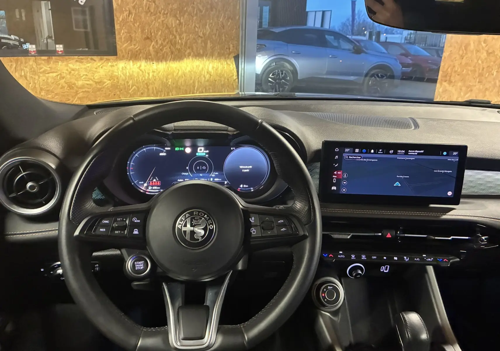 Vue intérieure centrée sur le volant noir d'Alfa Romeo Tonale 2023 avec tableau de bord digital et écran tactile GPS.