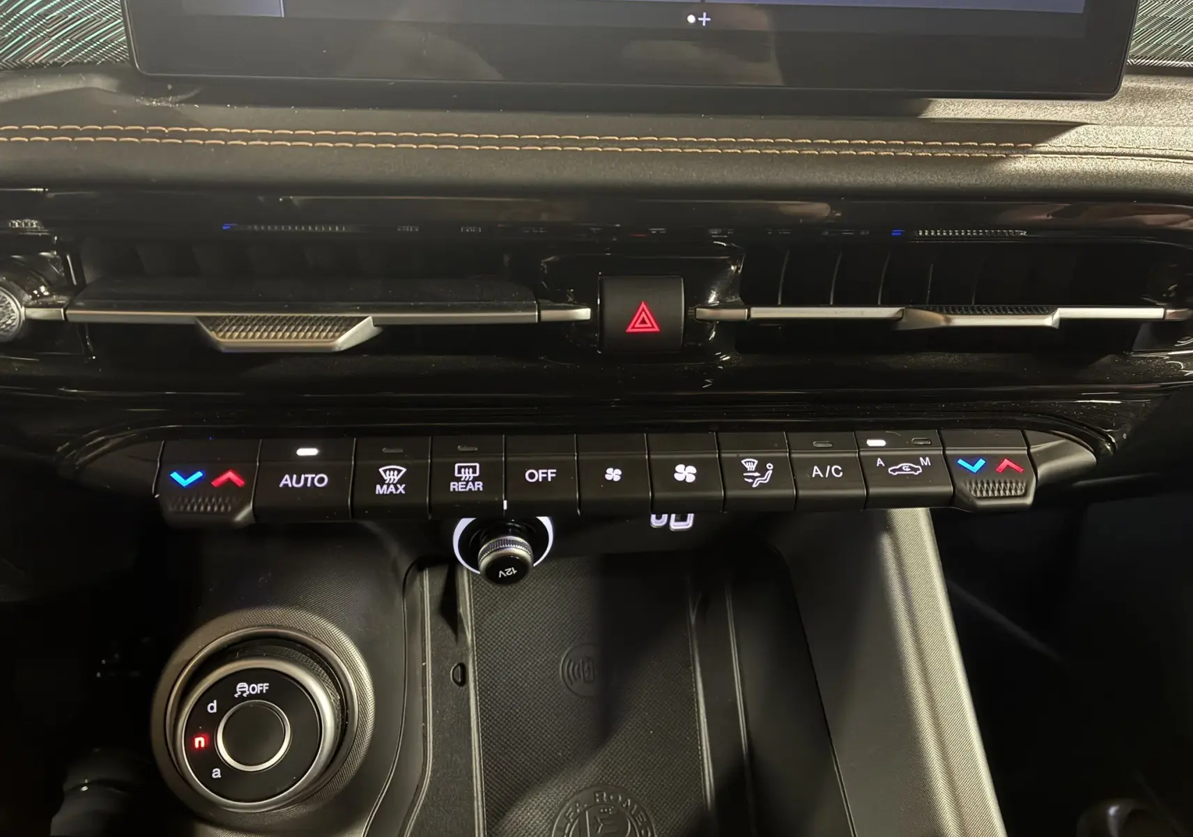 Vue rapprochée de la console centrale noire de l'Alfa Romeo Tonale 1.3 PHEV 280 BVA TI 2023 avec commandes climatisation et bouton hazard.