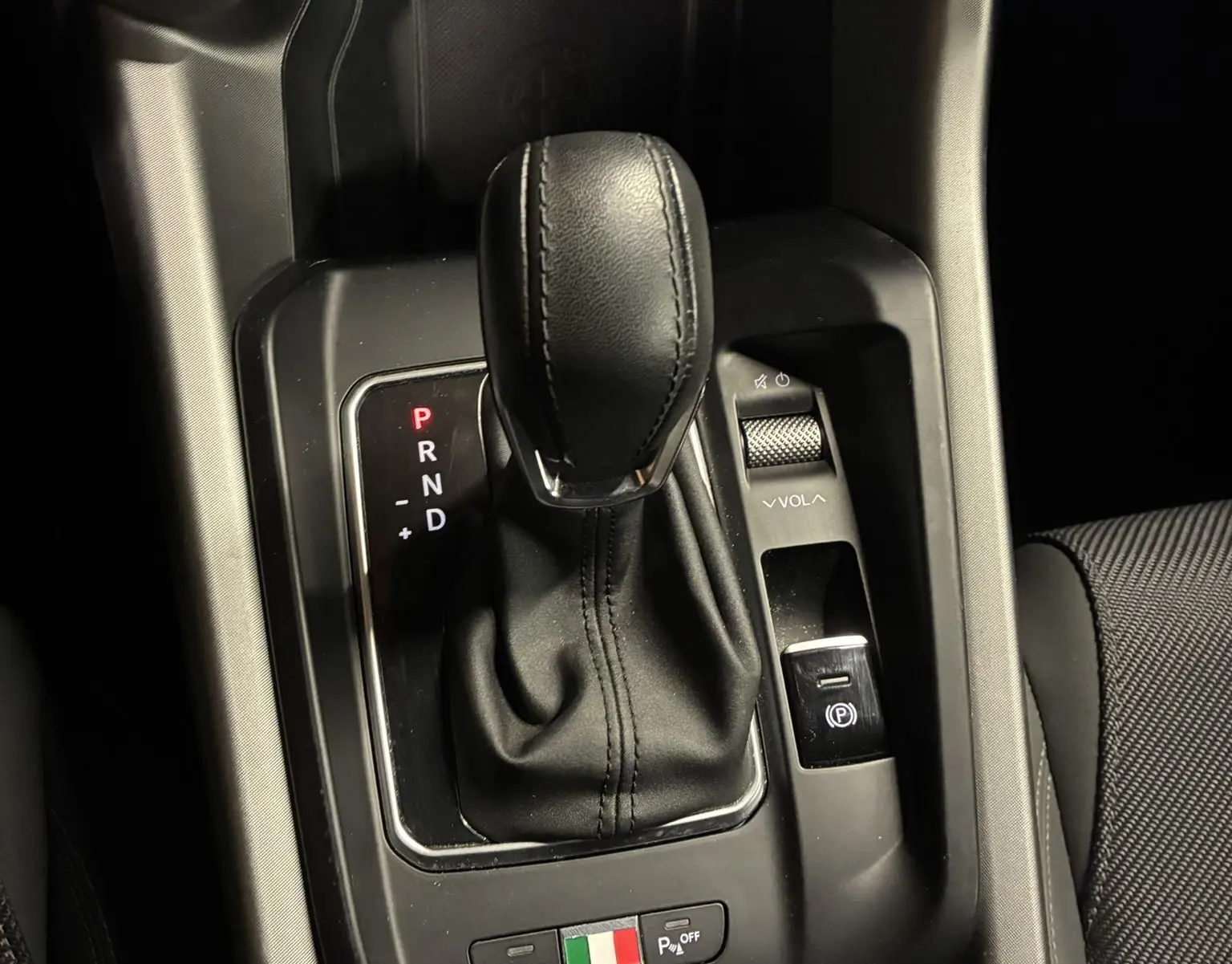 Gros plan sur la console centrale de l'Alfa Romeo Tonale 1.3 PHEV 280 BVA TI 2023, levier de vitesse cuir noir et commandes.