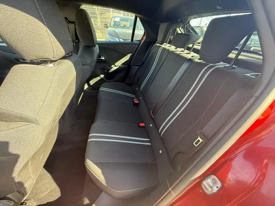 Vue intérieure côté droit sur les sièges arrière noirs avec bandes blanches d'une Opel Corsa rouge 2025.
