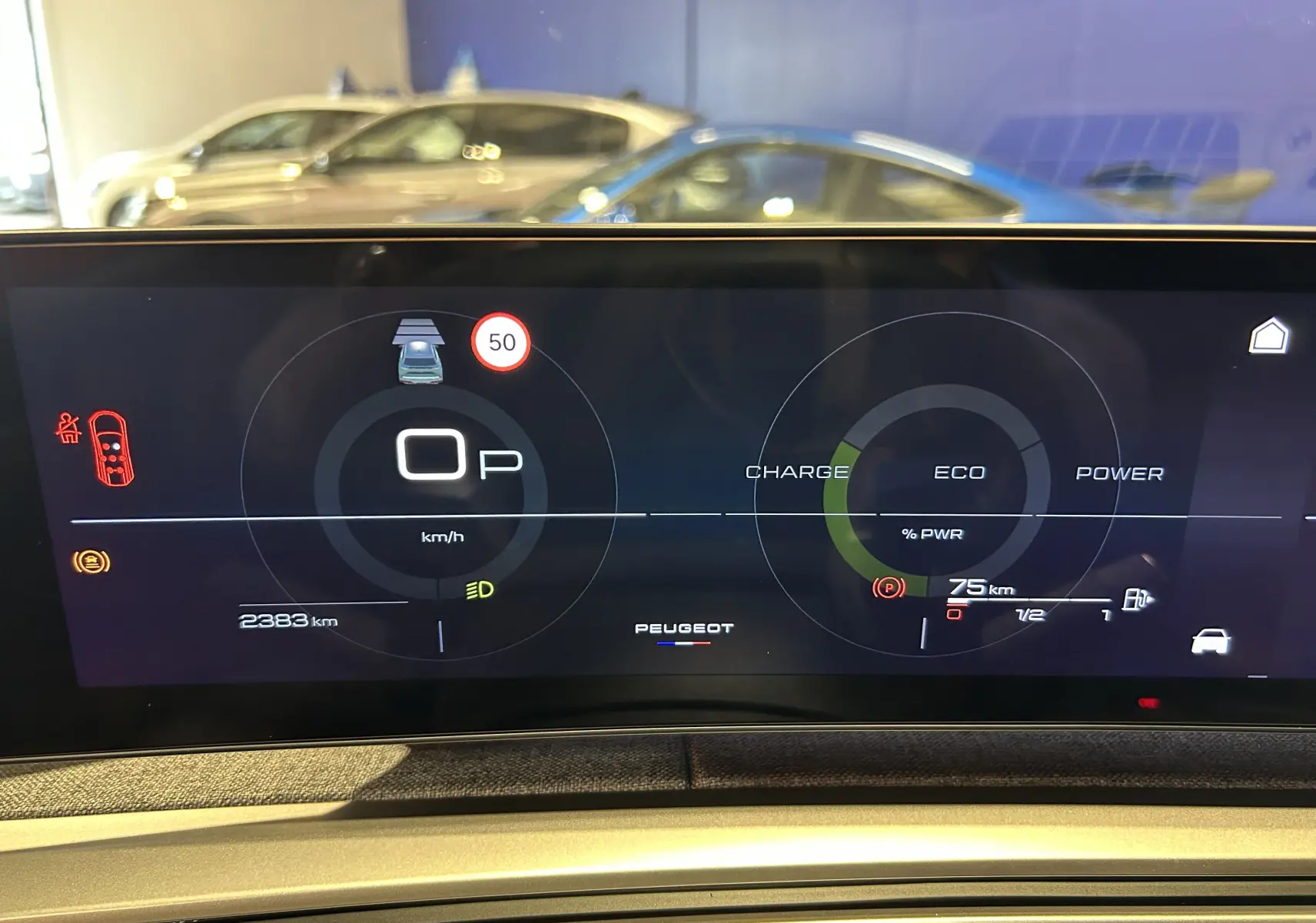 Tableau de bord numérique de Peugeot 5008 Hybrid gris titane, affichant vitesse, autonomie et mode éco en vue frontale.