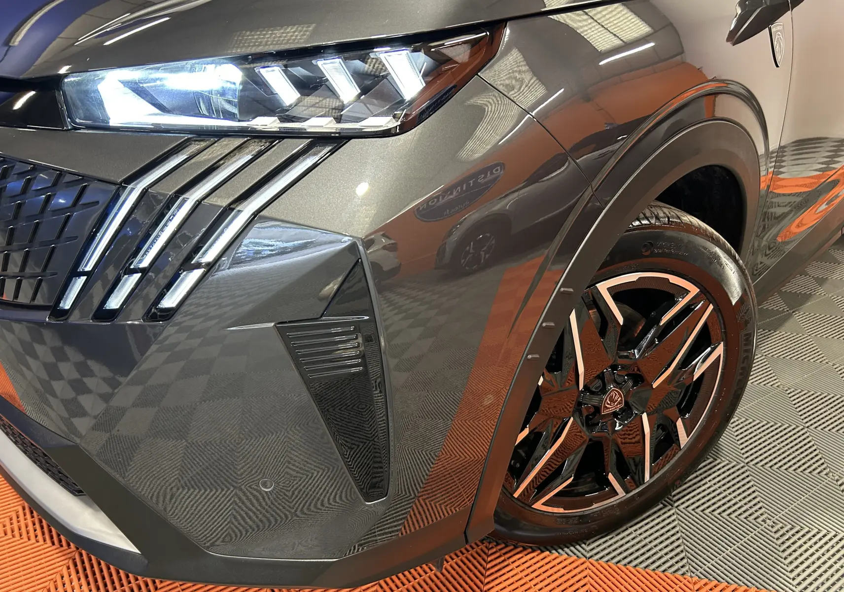 Gros plan sur l’avant droit gris titane du Peugeot 5008 Hybrid 145ch GT, mettant en valeur le phare LED et la jante noire stylisée.