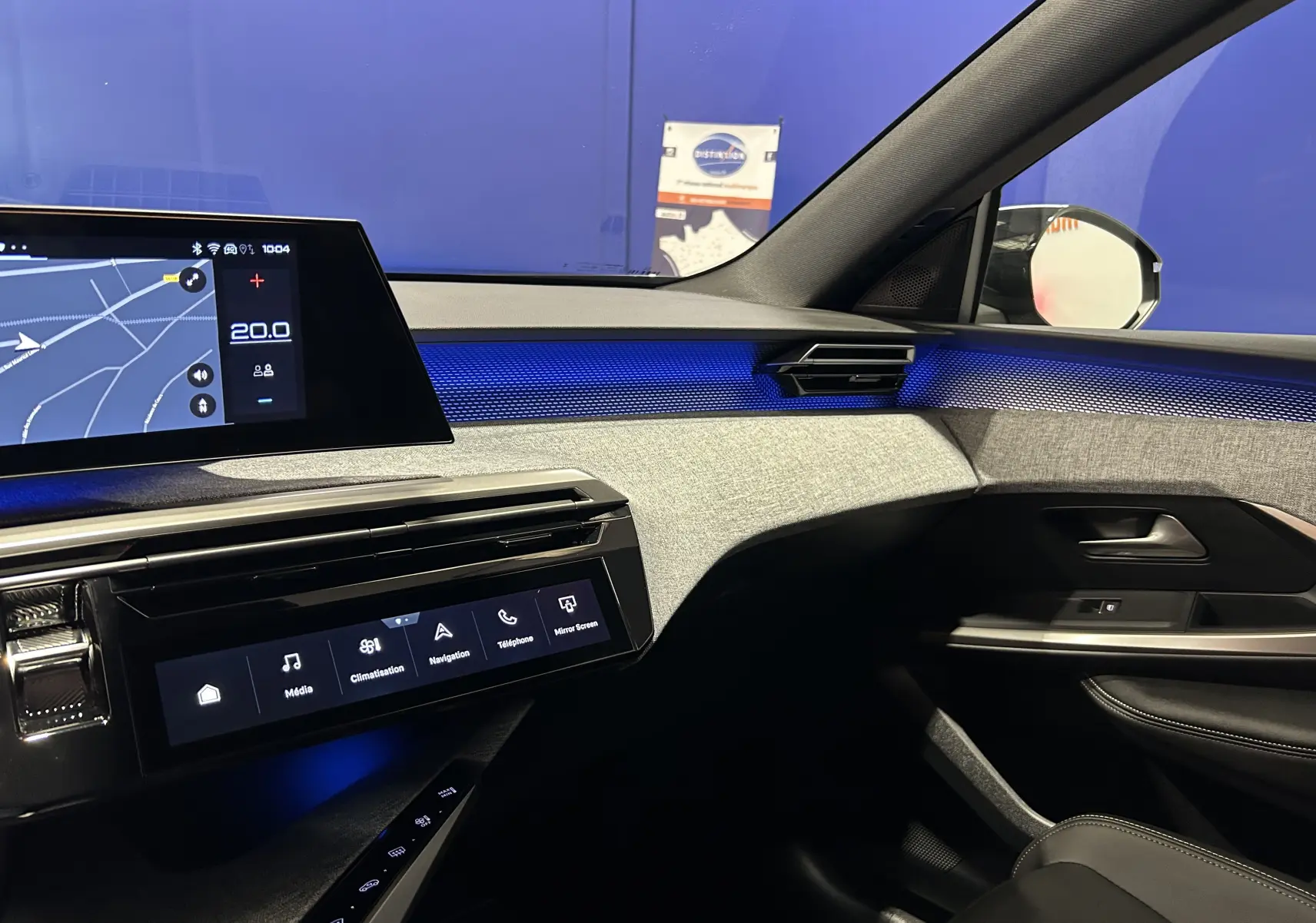 Vue intérieure côté passager du Peugeot 5008 Hybrid gris titane, avec éclairage d'ambiance bleu et écran tactile de navigation.