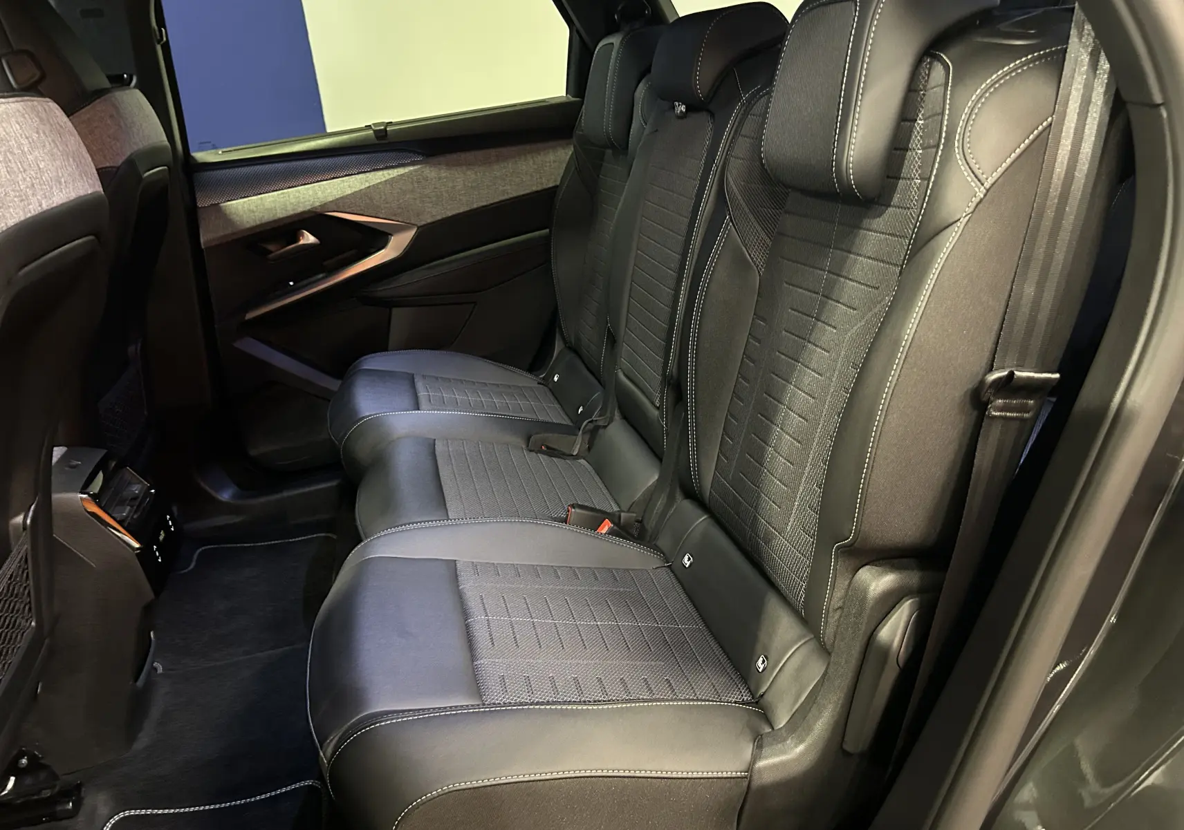 Vue latérale intérieure des sièges arrière noirs avec surpiqûres blanches du Peugeot 5008 Hybrid 2025 gris titane.