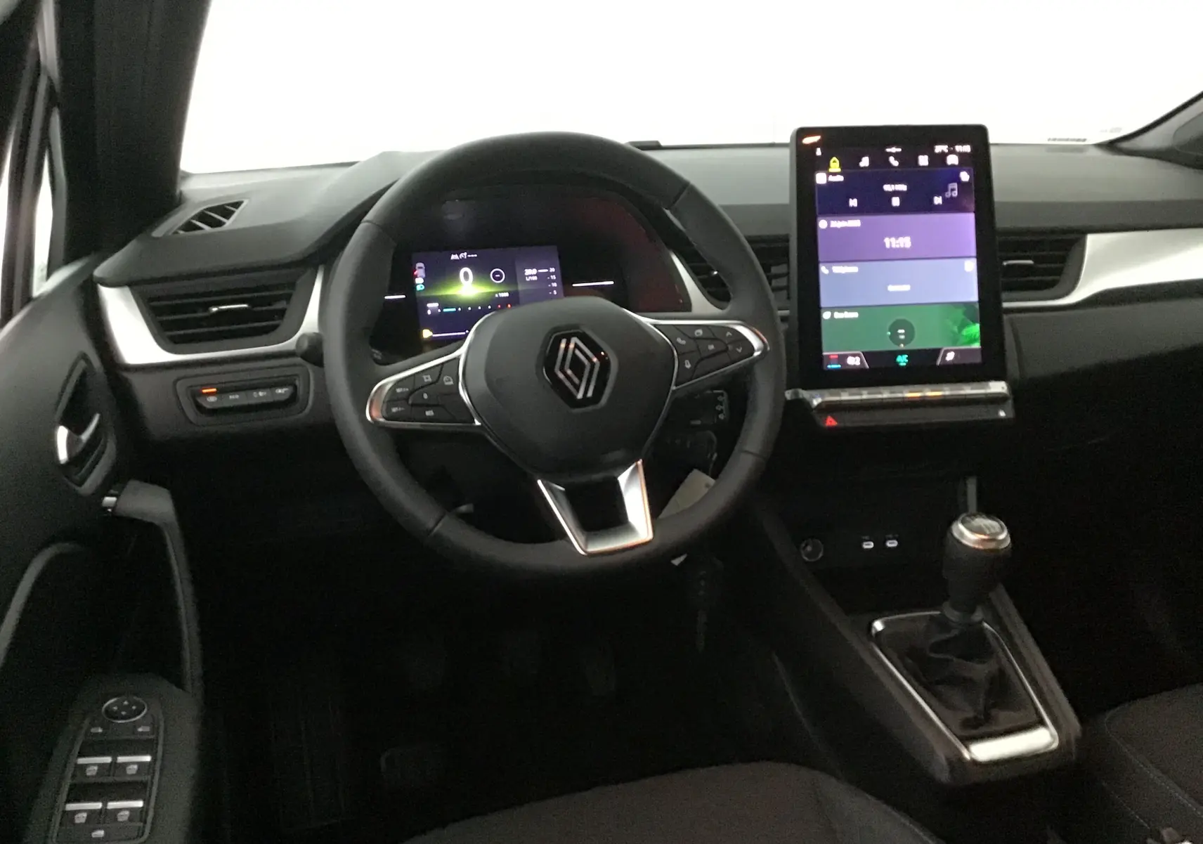 Vue intérieure frontale du tableau de bord du Renault Captur 2025, avec volant multifonction et écran tactile vertical.