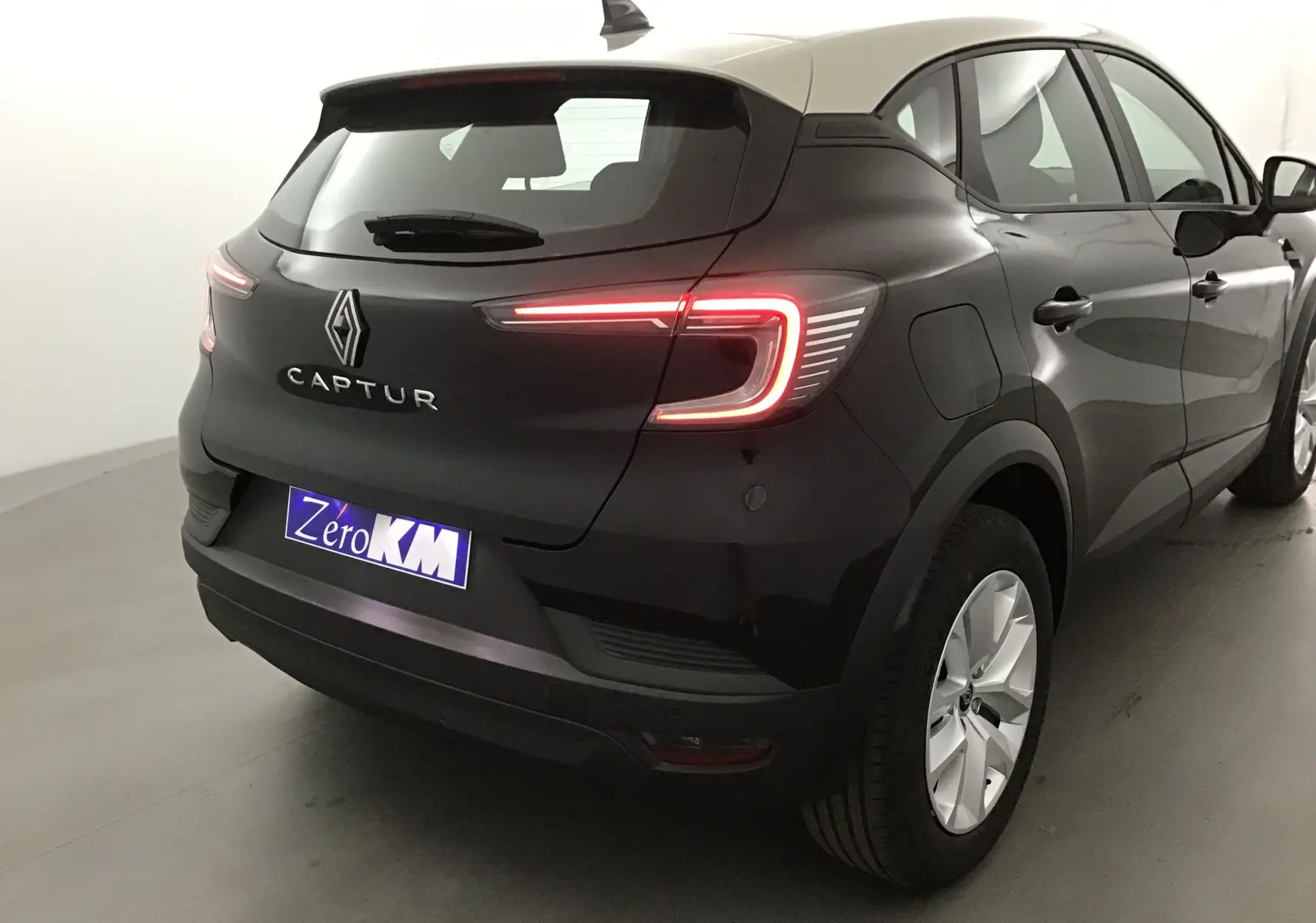 Vue 3/4 arrière droite du Renault Captur 2025 noir et gris perle avec feux LED allumés et jantes argentées.