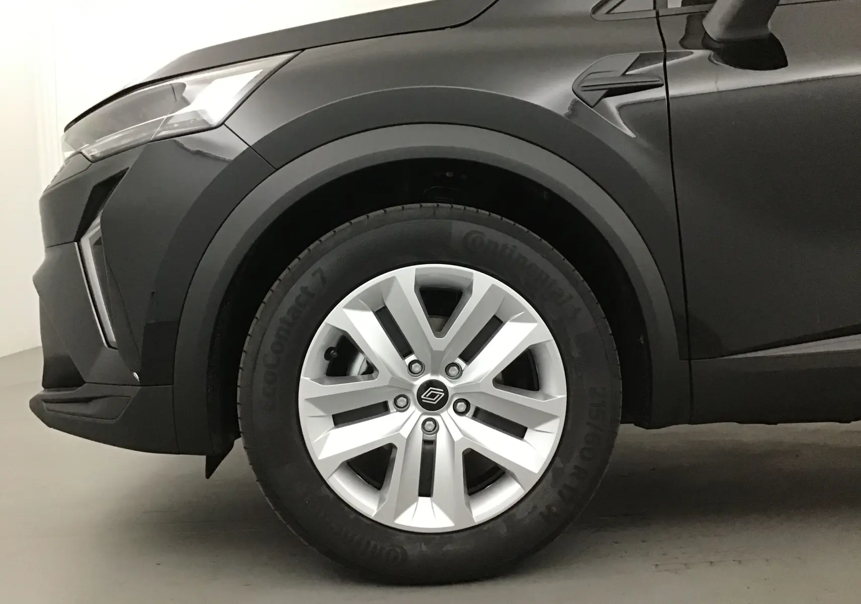 Gros plan sur la roue avant gauche du Renault Captur 2025 noir/gris perle avec jante argentée et détails de carrosserie.