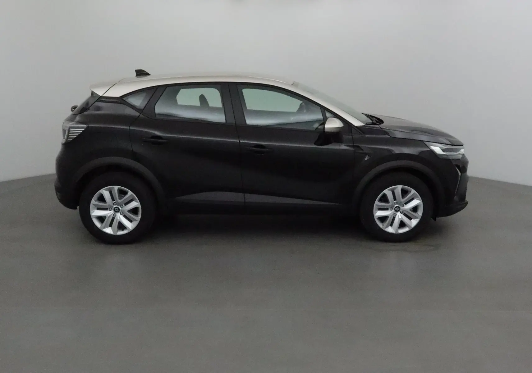 Profil côté droit du Renault Captur 2025 noir avec toit gris perle et jantes argentées dans un studio neutre.