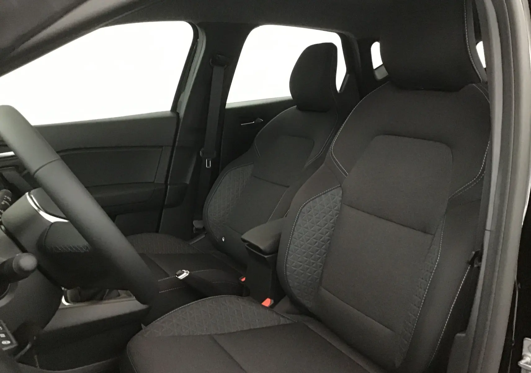 Intérieur du Renault Captur 2025, vue côté gauche sur les sièges avant noirs avec surpiqûres grises et volant partiel.