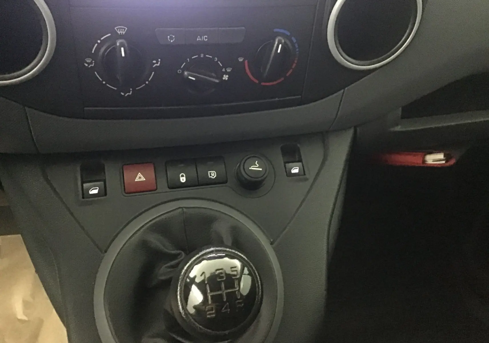 Gros plan sur la console centrale noire du Citroën Berlingo 2018, mettant en valeur le levier de vitesse manuel et les commandes climatiques.
