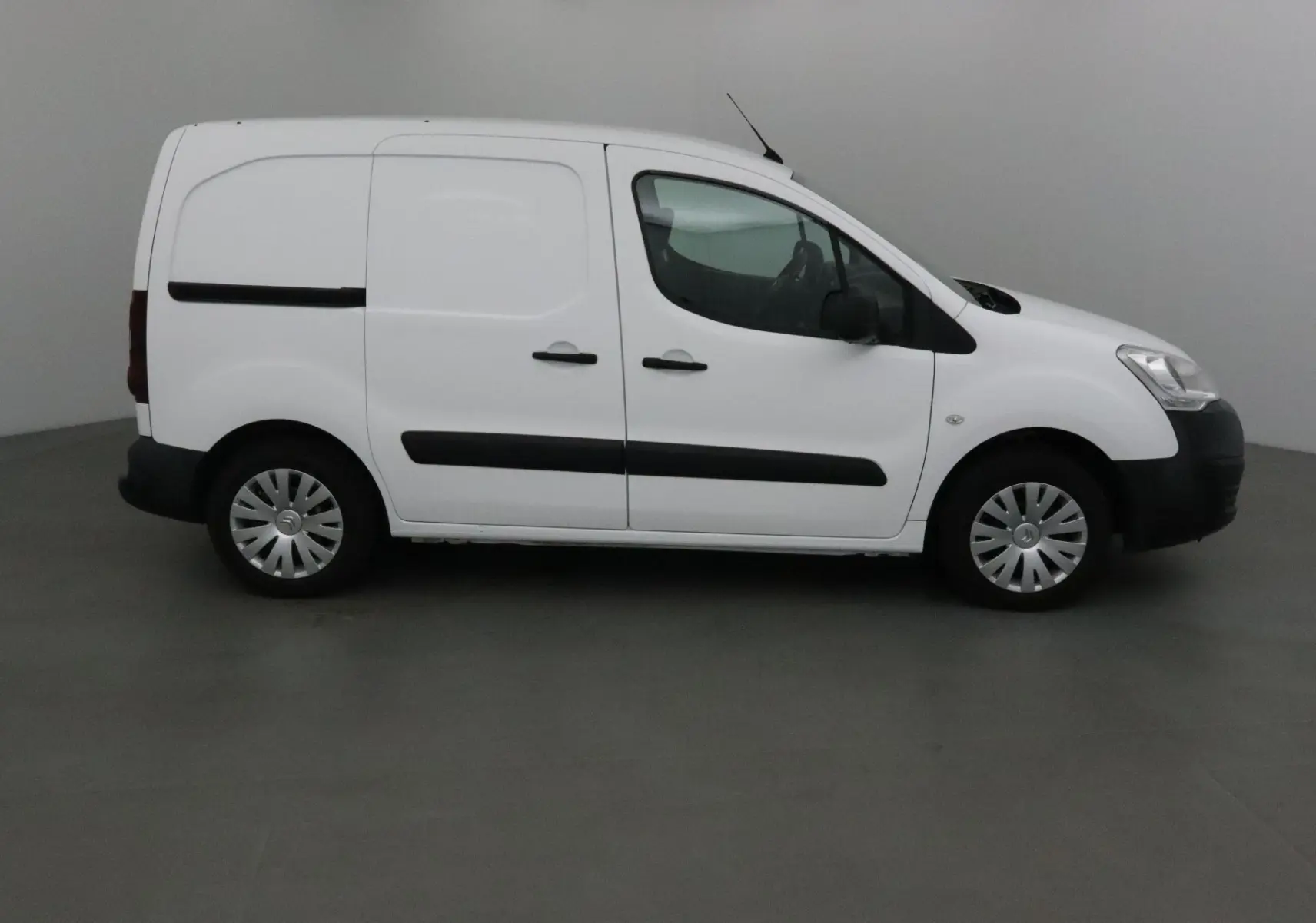 Profil côté droit d’un utilitaire blanc Citroën Berlingo M 1.6 BlueHDi 75 Business avec portes latérales noires.