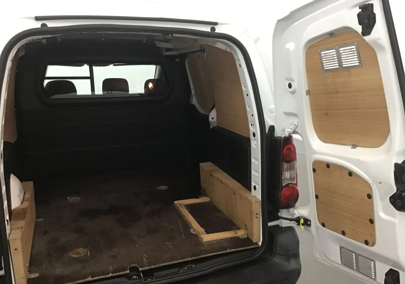 Vue arrière ouverte du Citroën Berlingo blanc 2018 montrant l'espace de chargement avec habillage bois intérieur.