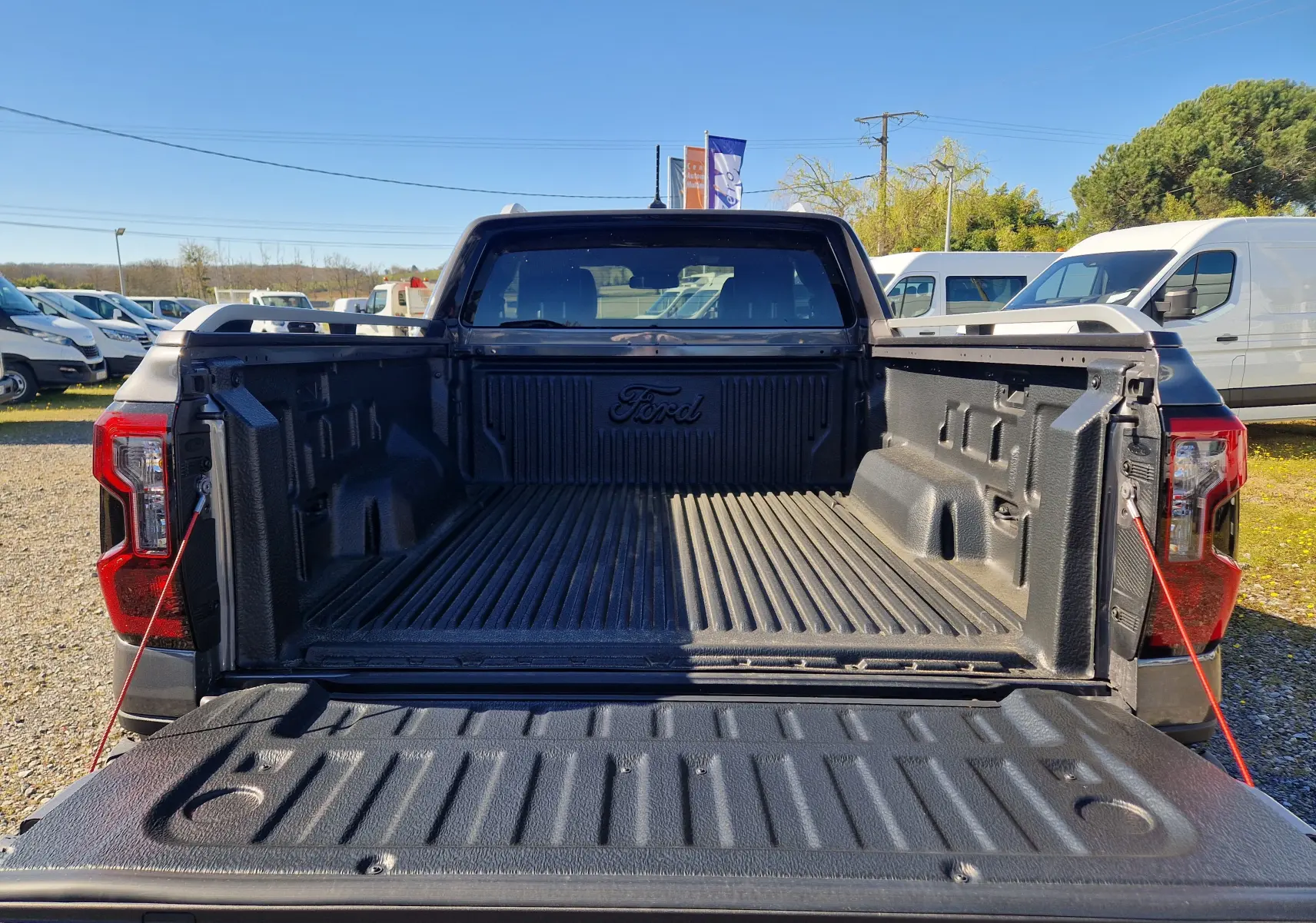 Vue arrière du Ford Ranger Super Cabine gris carbone avec benne ouverte et revêtement de protection noir.