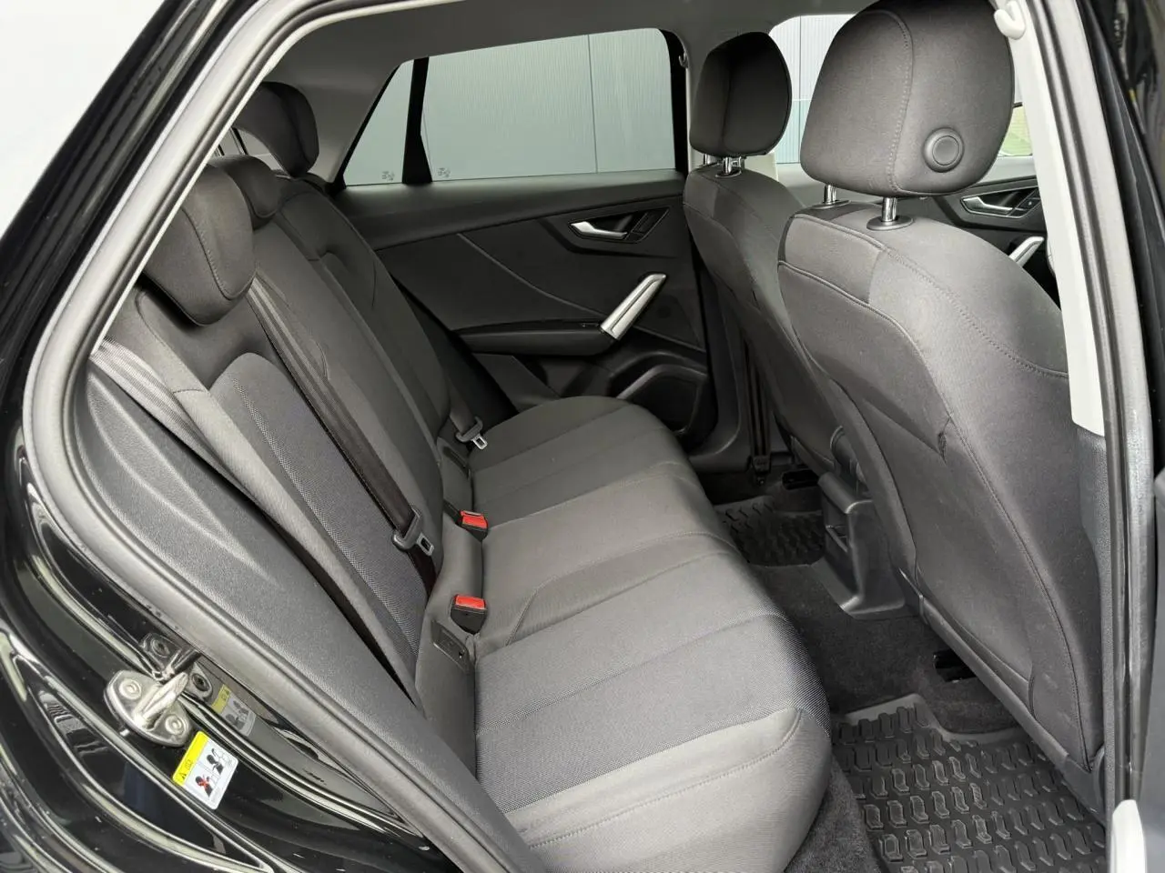 Vue intérieure côté droit sur les sièges arrière gris foncé d'un Audi Q2 noir métallisé 2023 finition S line.