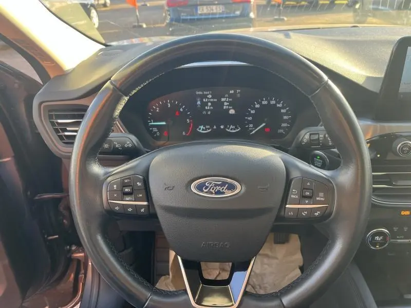 Vue intérieure centrée sur le volant cuir multifonction d'une Ford Kuga 2021 gris Magnetic avec tableau de bord numérique.