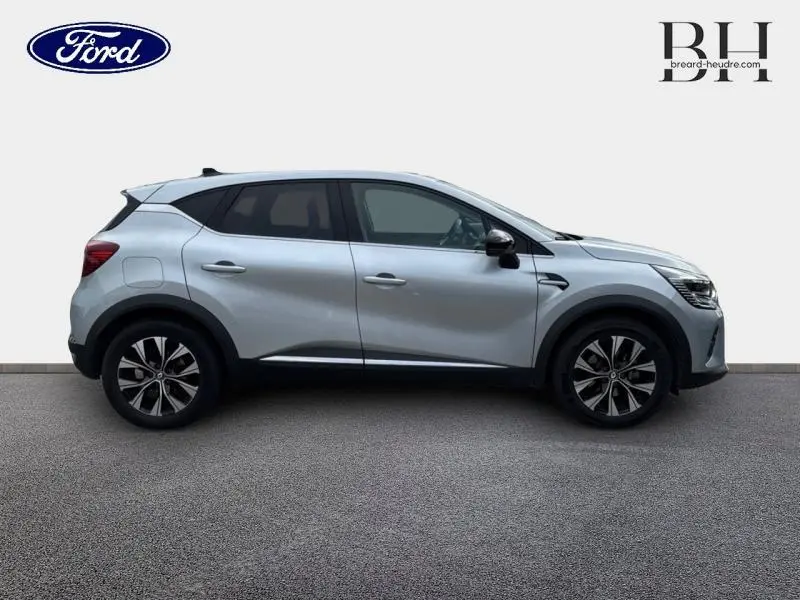 Profil droit d'un Renault Captur 1.6 E-Tech hybride 2023 en gris Highland avec jantes alliage et vitres teintées.