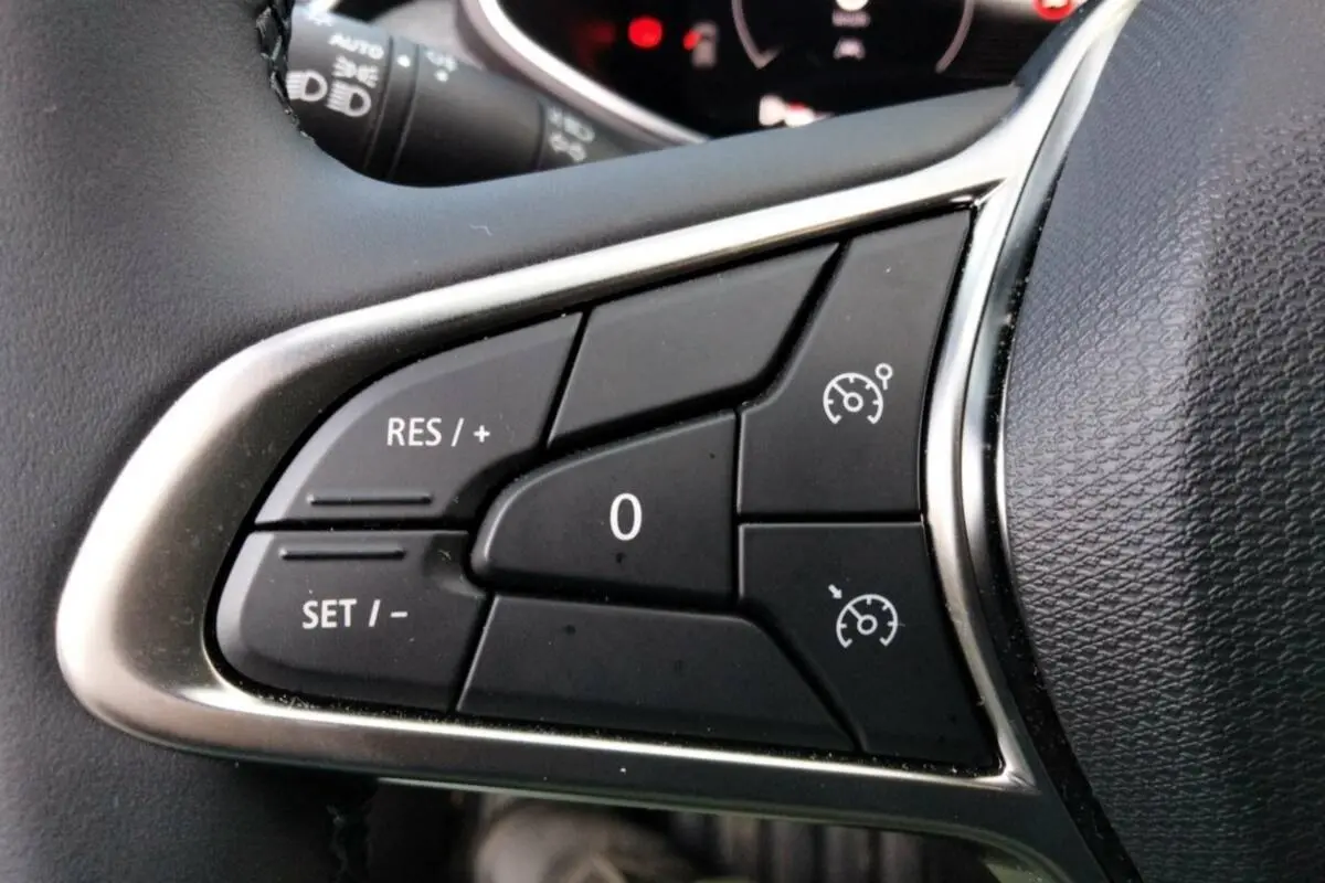 Gros plan sur les commandes du régulateur de vitesse au volant cuir de la Renault Clio V TCE 90 Techno Plus.