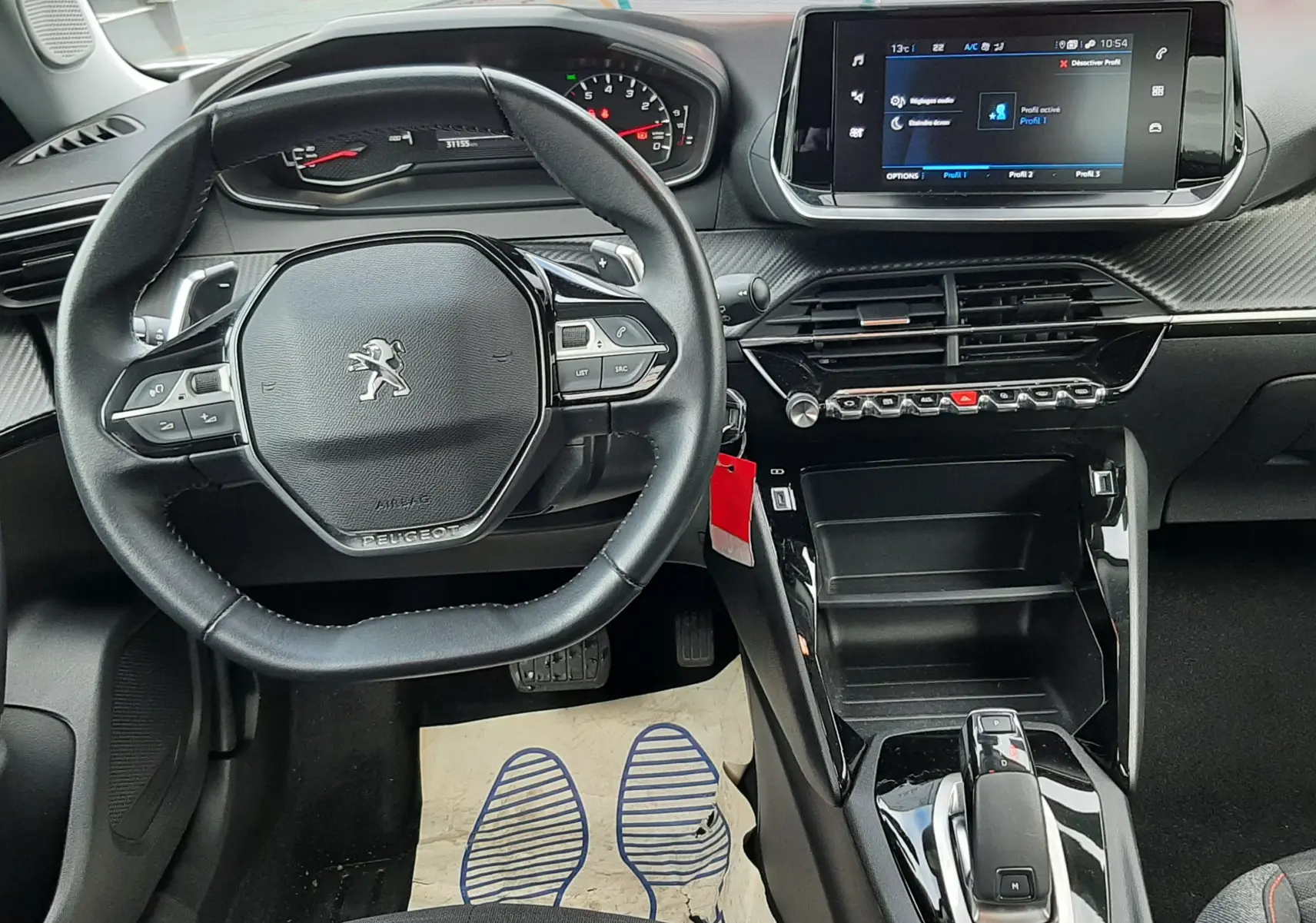 Vue intérieure du poste de conduite du Peugeot 2008 2021, volant compact, écran tactile central et console noire brillante.