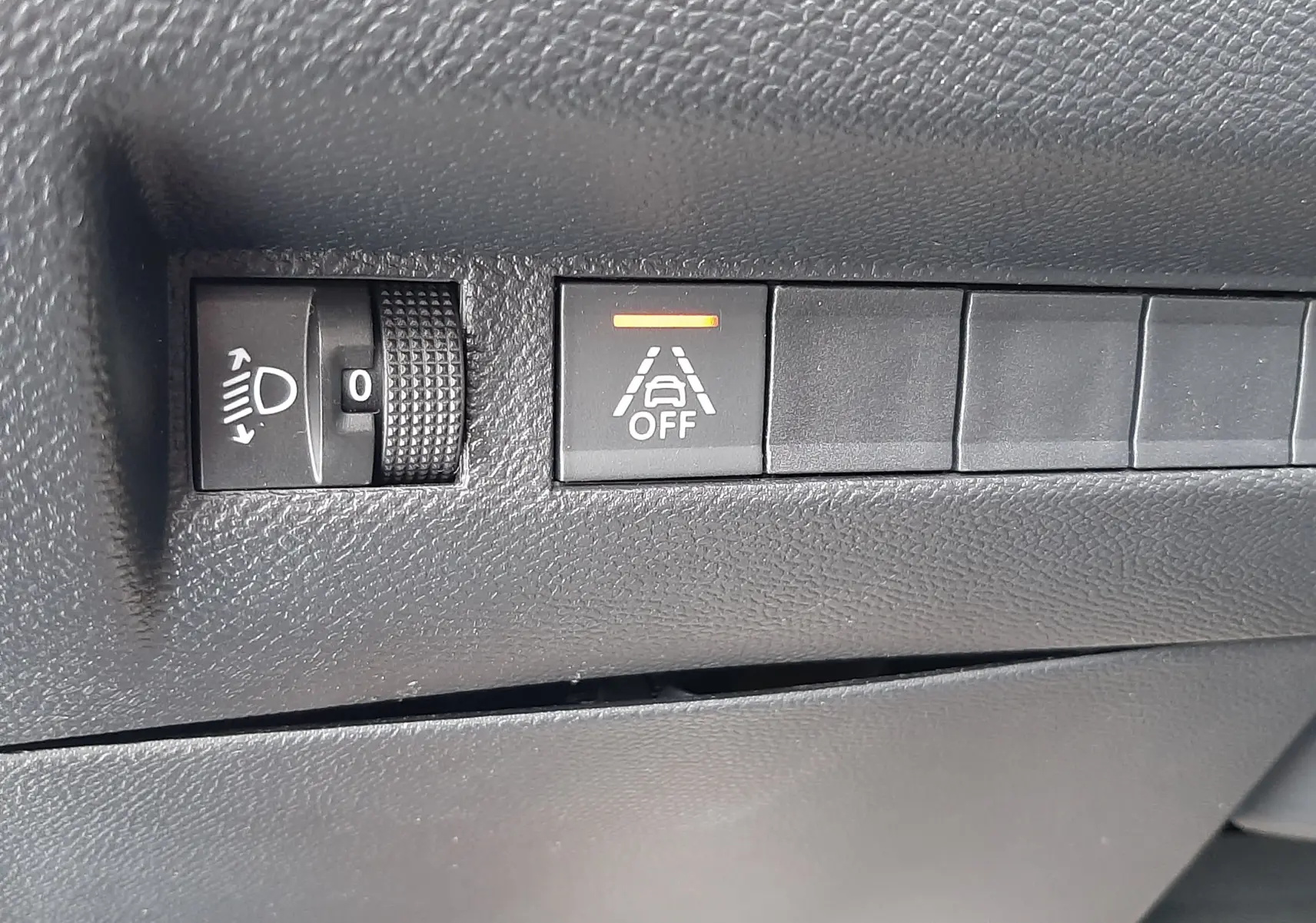 Détail des commandes d'assistance à la conduite sur le tableau de bord noir du Peugeot 2008 blanc 2021.