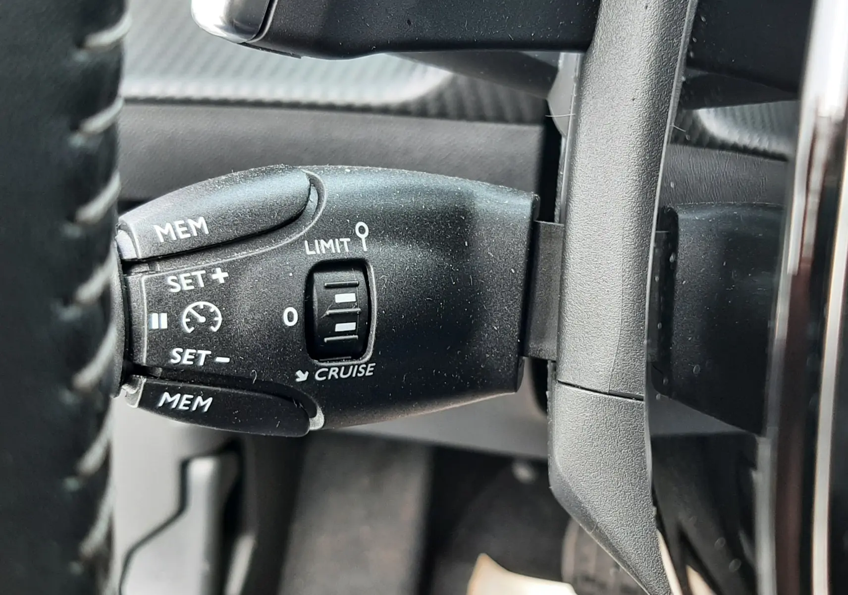 Gros plan sur la commande de régulateur de vitesse à gauche du volant d'un Peugeot 2008 blanc de 2021.