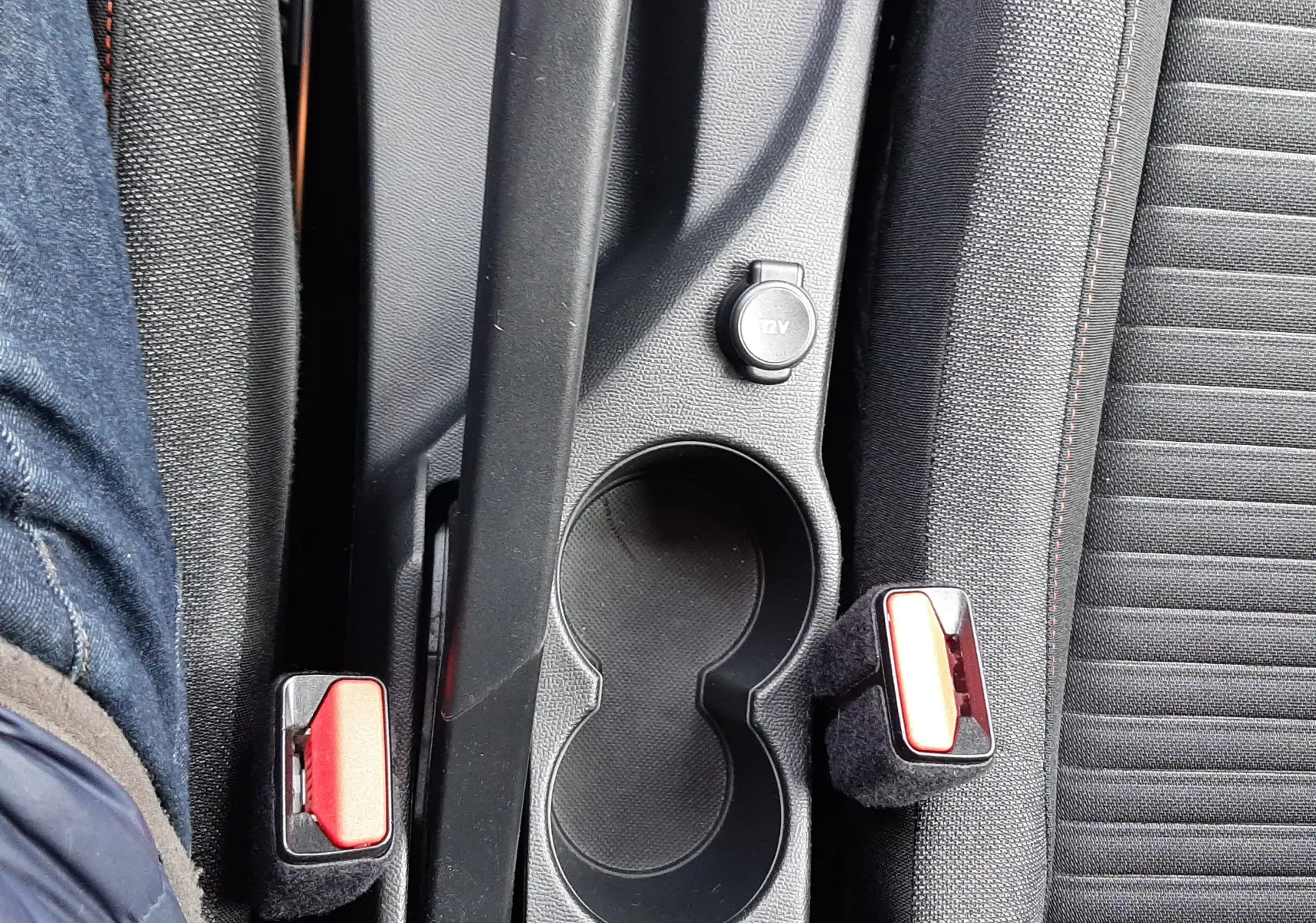 Vue plongeante sur la console centrale noire du Peugeot 2008, avec frein à main, porte-gobelets et ceintures rouges.