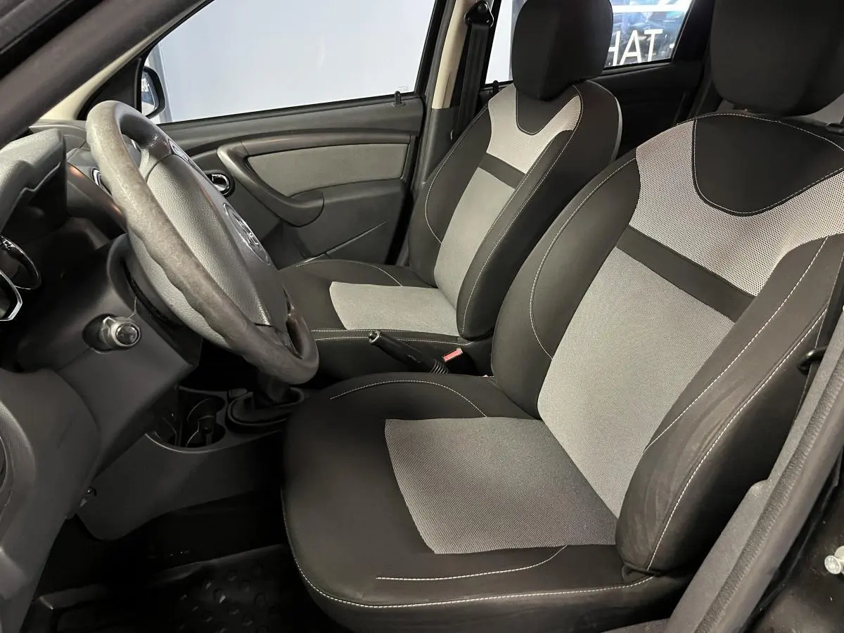 Intérieur avant droit du Dacia Duster 2016, sièges bicolores gris et noir avec volant et levier de vitesse visibles.