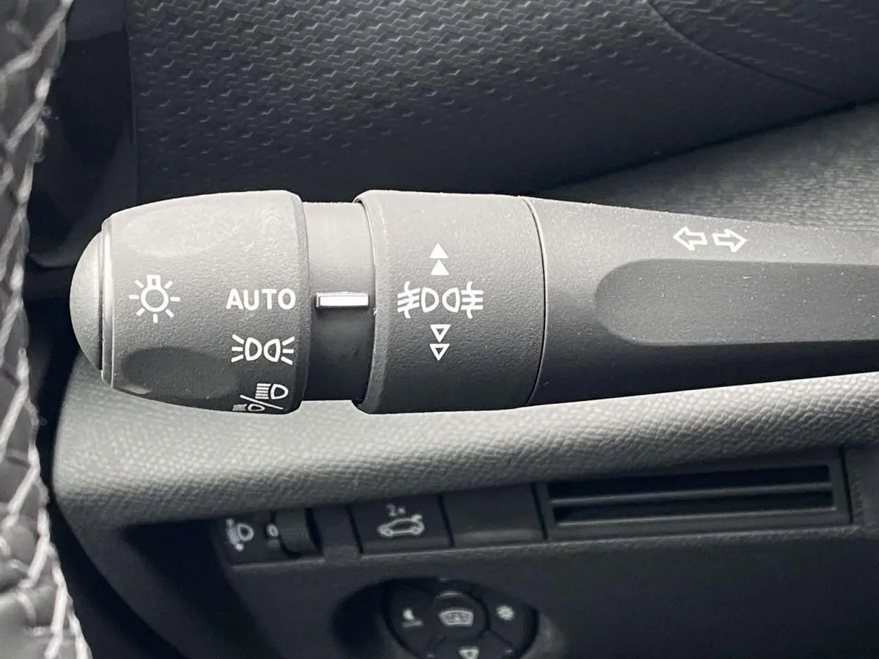 Gros plan sur la manette de commande des feux et clignotants dans l'habitacle d'une Citroën C4 X rouge Elixir.