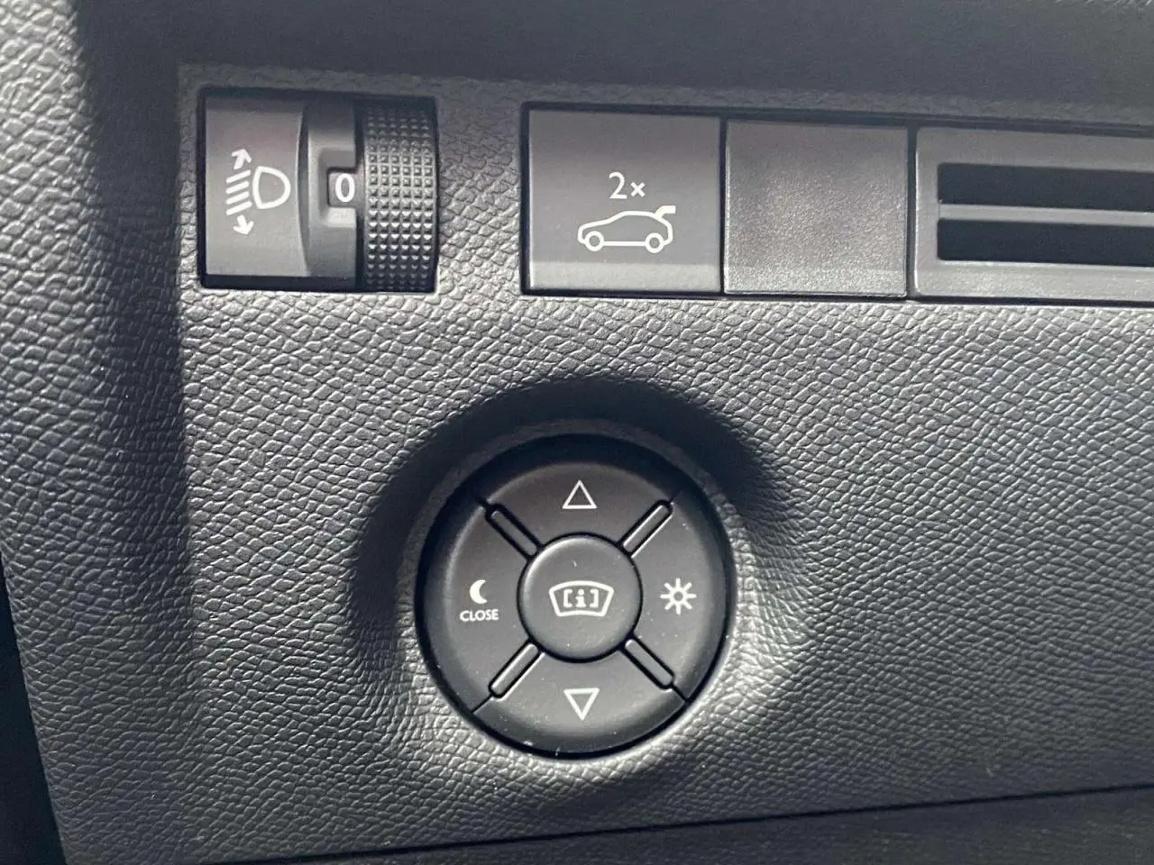 Gros plan sur les commandes de réglage des rétroviseurs et des phares dans une Citroën C4 X rouge Elixir 2022.