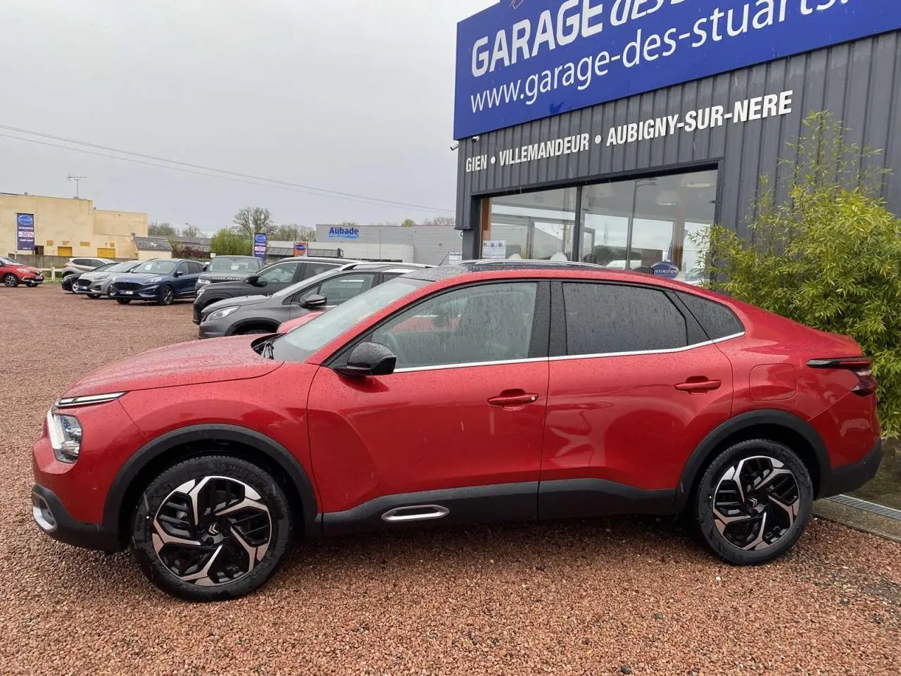 Profil côté gauche d'une Citroën C4 X rouge Elixir 2022 avec jantes alliage et toit ouvrant électrique visible.