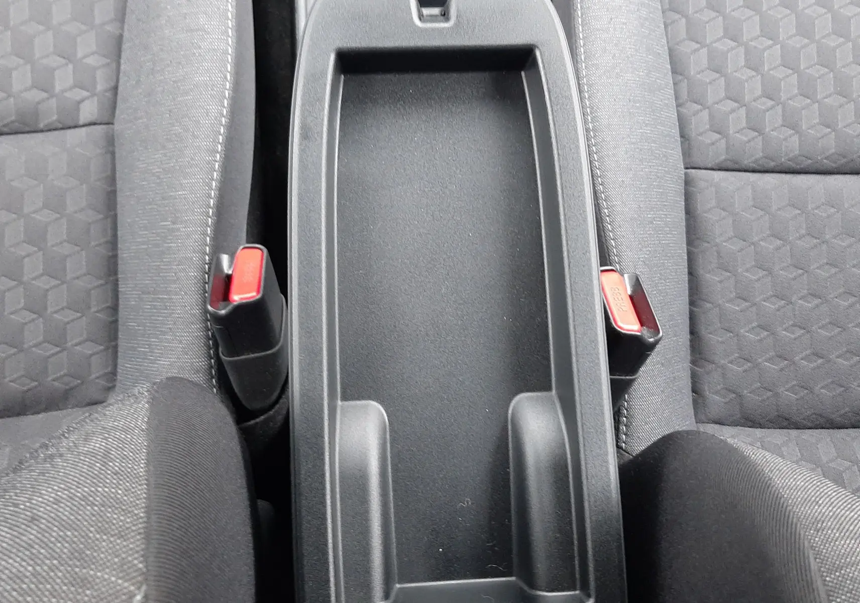 Vue plongeante sur la console centrale noire et les sièges tissu gris foncé de la Toyota Yaris 2023 hybride.